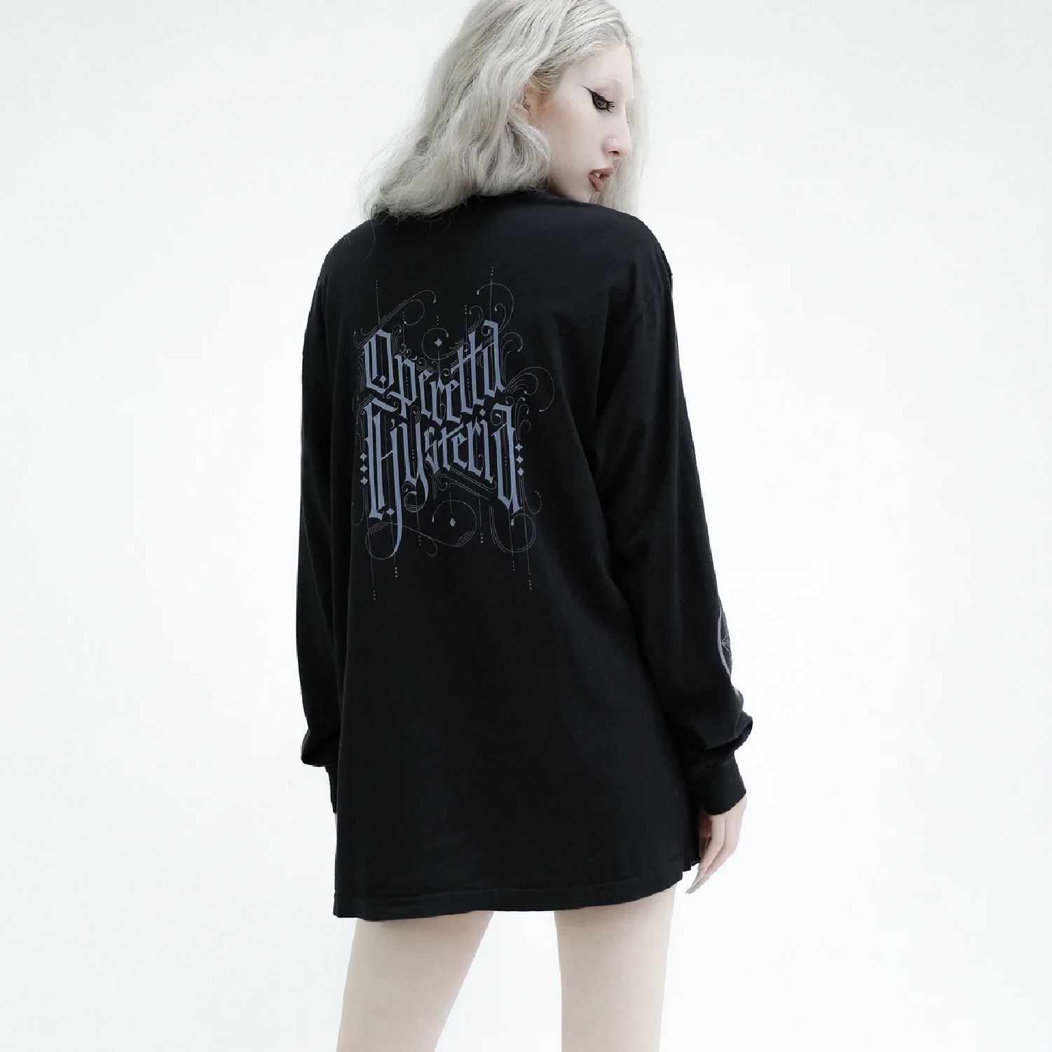A person seen from behind wearing a black long-sleeve shirt with blue, ornate, gothic-style text on the back.