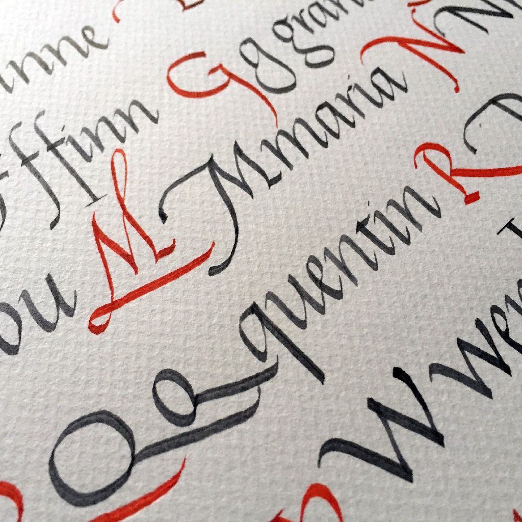 Close-up of decorative calligraphy letters in black and red on textured paper