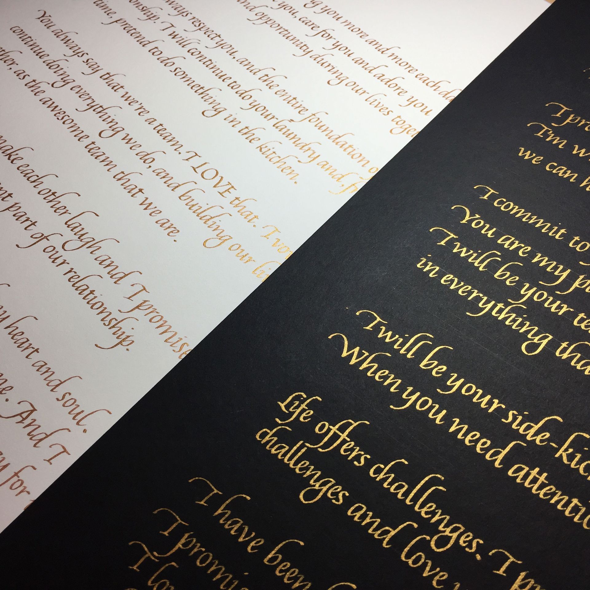 Open book with elegant gold serif text on black pages beside a cream page with cursive writing