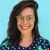 Smiling Maria Montes with glasses and dark hair against a turquoise wall, wearing a navy polka dot shirt