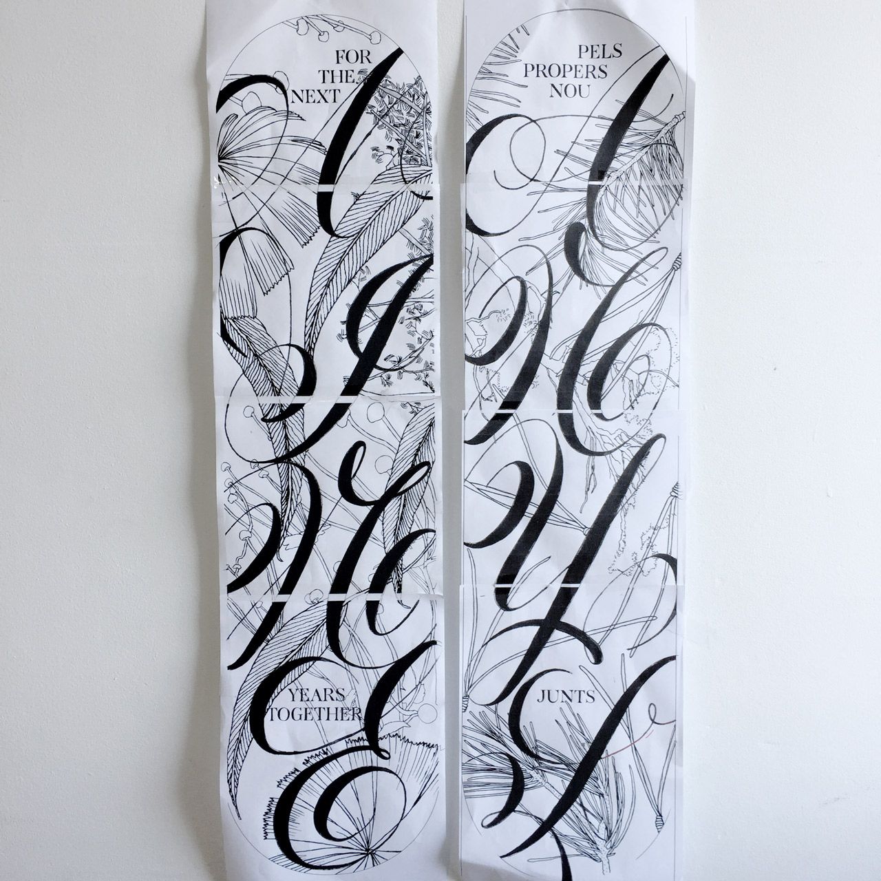 Two vertical paper strips feature elaborate, ornate black calligraphy and sketch-like patterns on a white background.