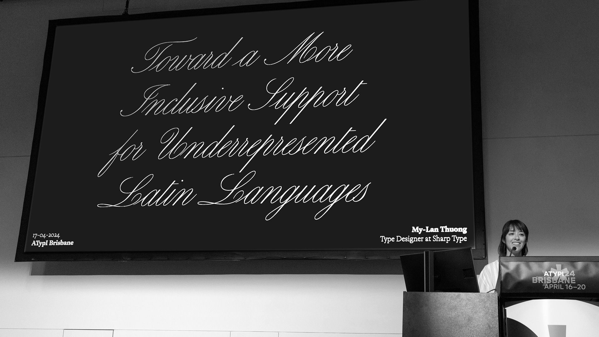 Black sign reading “Tourist & More Industries Support for Underserved Latin Languages” on a wall