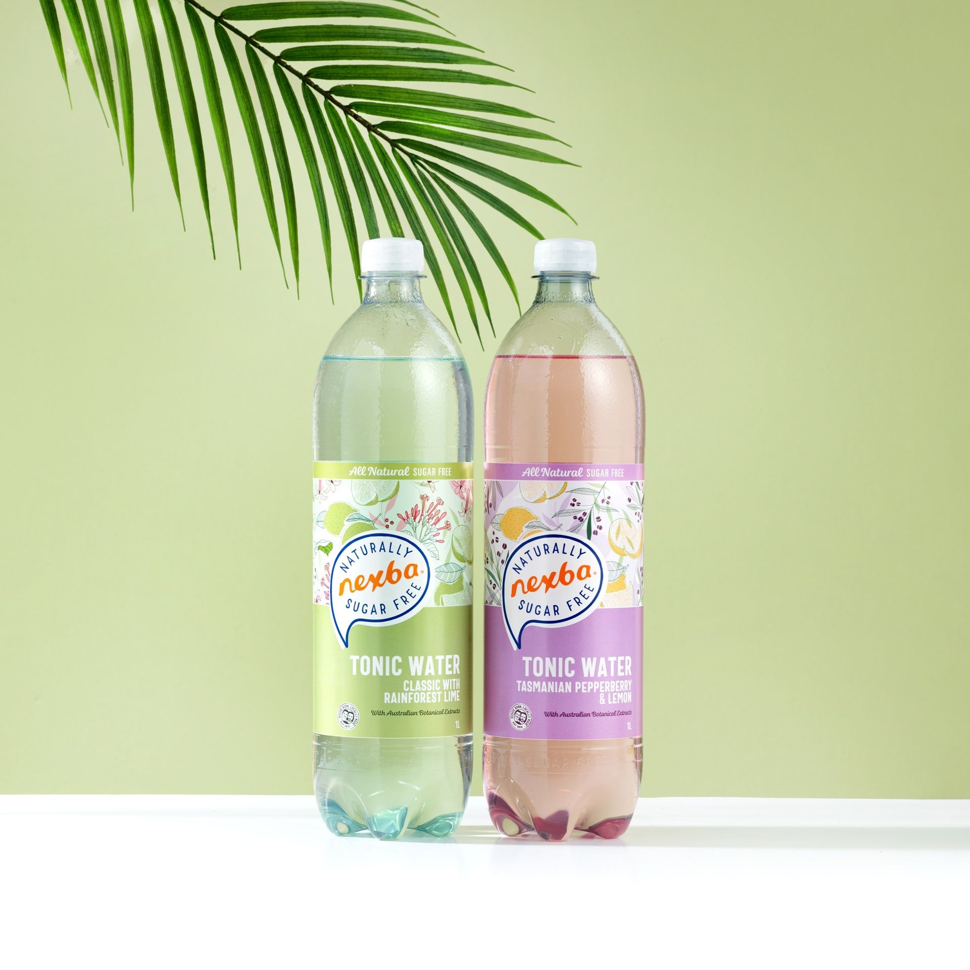 Two bottles of Nexba tonic water, one green and one pink, stand side-by-side against a light green background with a leaf.