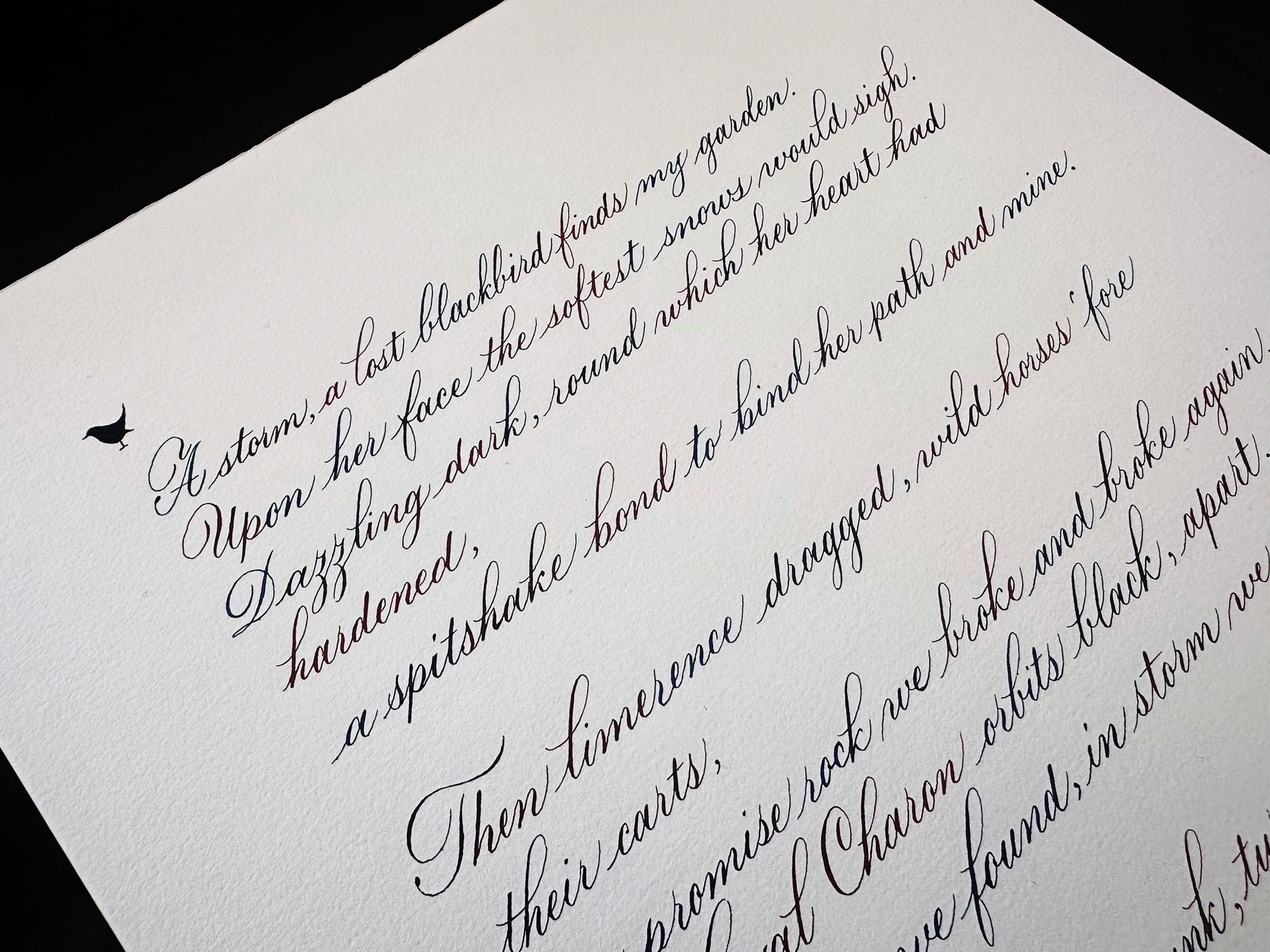 A small, black silhouette of a bird next to elegant, handwritten cursive script on white paper.