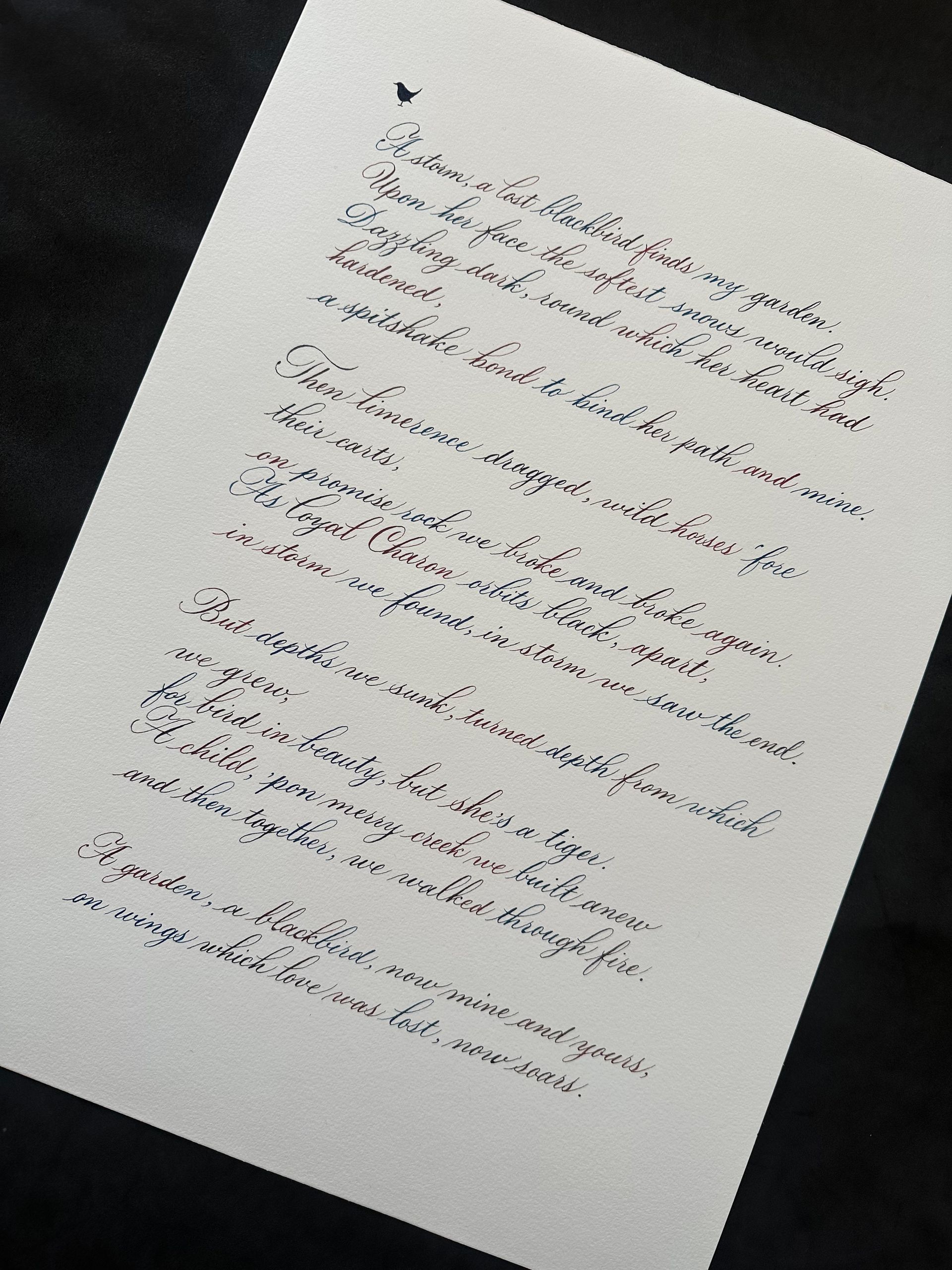 A piece of white paper with handwritten cursive text in dark ink, angled on a dark background.