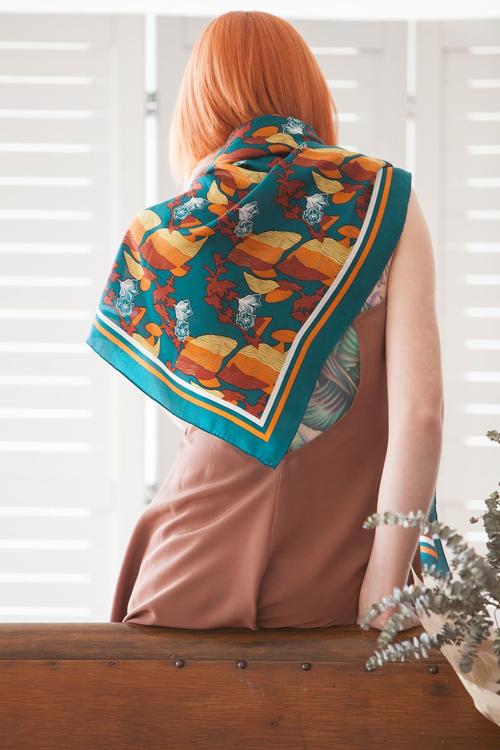 Woman seen from behind wearing a colorful patterned scarf in a bright room