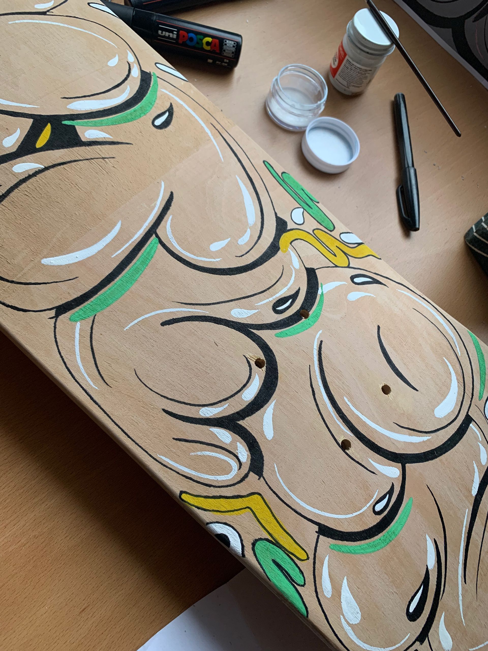 Decorative floral painting on cardboard with beige, black, green, and yellow accents; paint jar and brush nearby