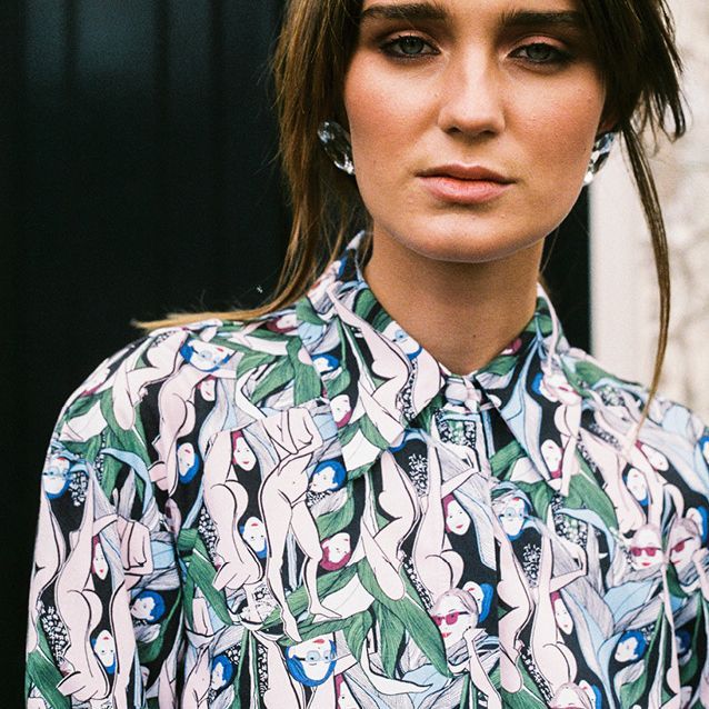 Portrait of a woman in a patterned button-up shirt against a neutral background
