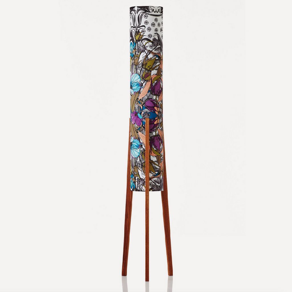 Tall narrow abstract patterned sculpture with three long wooden legs on a white background