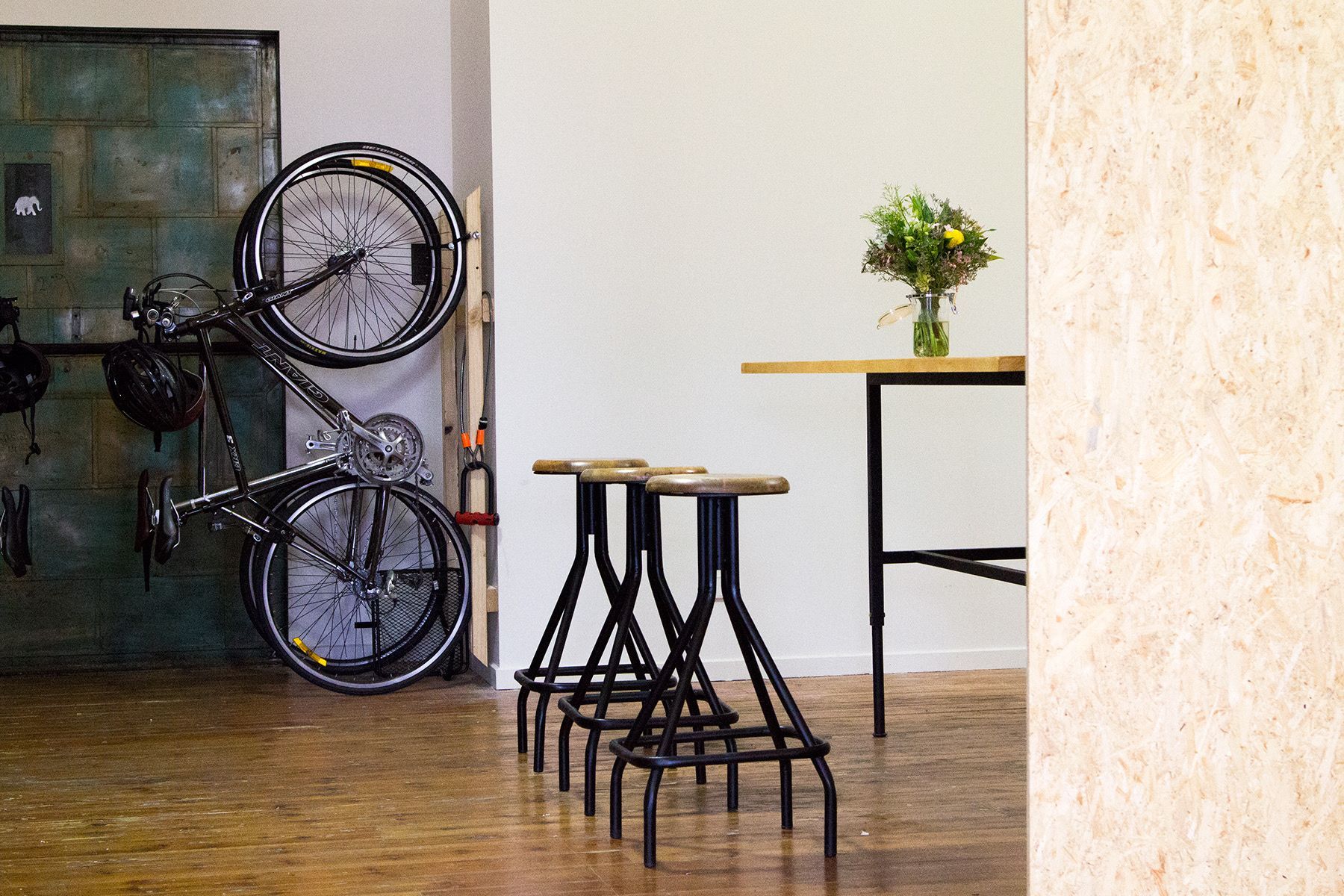 Minimalist room with stacked black chairs, a small table with flowers, and a bicycle wheel decoration