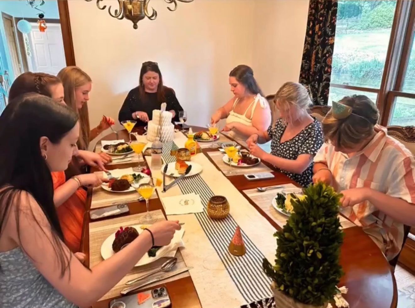 A group of people at a table, eating a meal in a well-lit dining room.