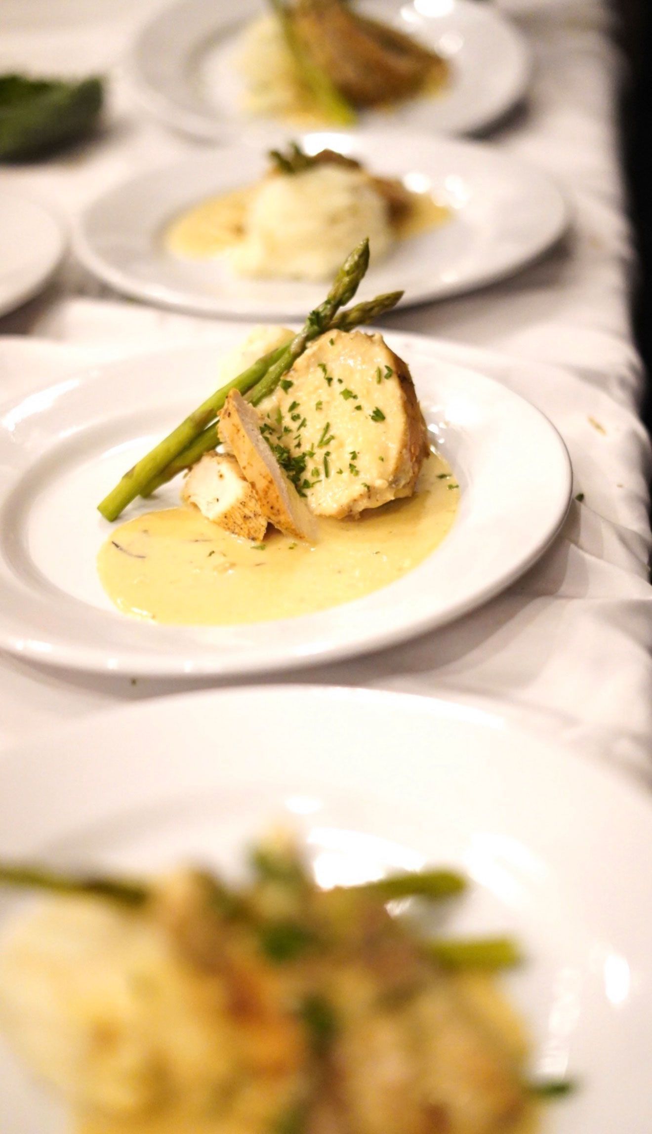 Plated meal with asparagus and creamy sauce, prepared for a dining event.