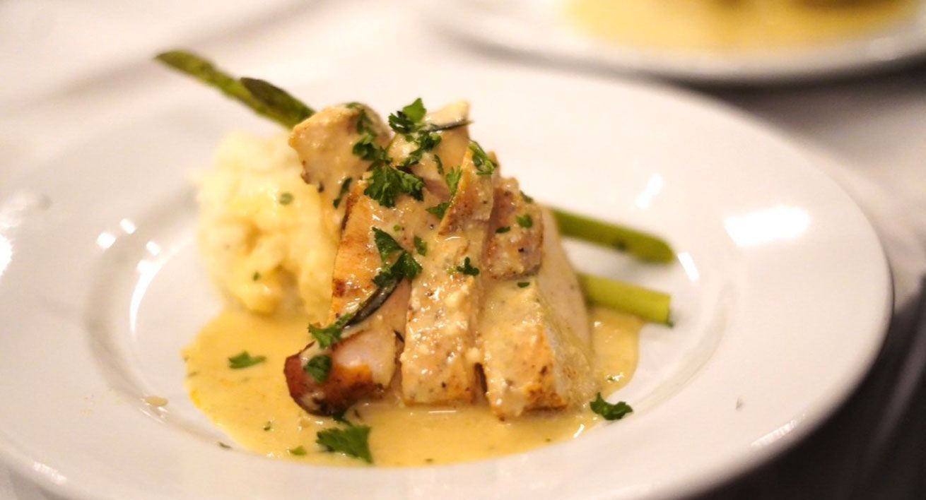 Chicken breast with gravy, asparagus, and mashed potatoes on a white plate.