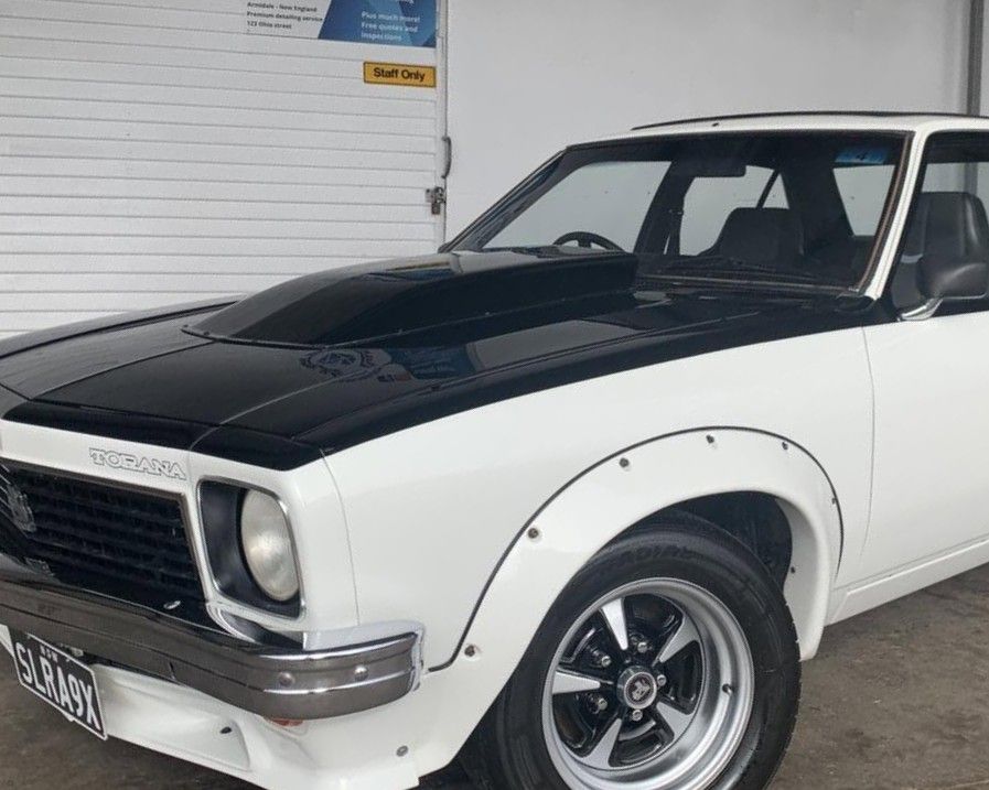 Classic White Coupe With Black Hood and Fender Flares Parked in a Garage — Diamond Glow Auto Detailing in Armidale, NSW