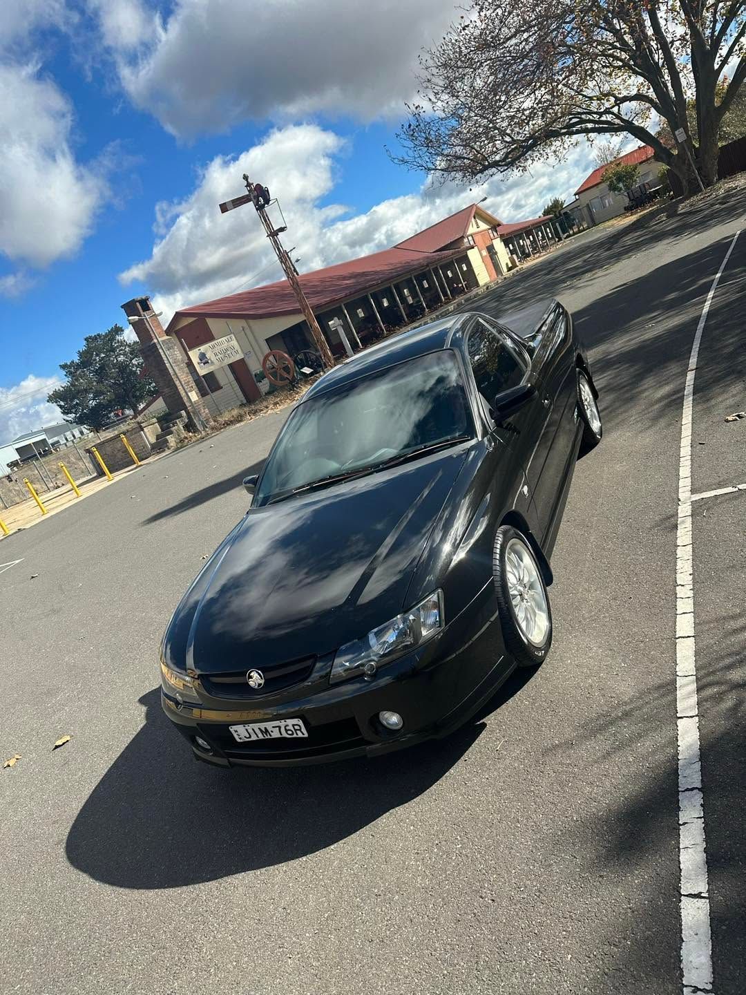 Black Sedan Parked in A Lot Beside a Red Roofed Building — Diamond Glow Auto Detailing in Armidale, NSW