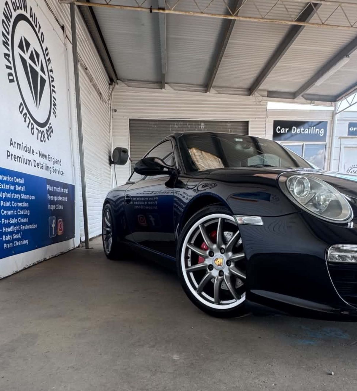 Black Porsche convertible parked in a showroom, angled front view under a metal roof. — Diamond Glow Auto Detailing in Armidale, NSW