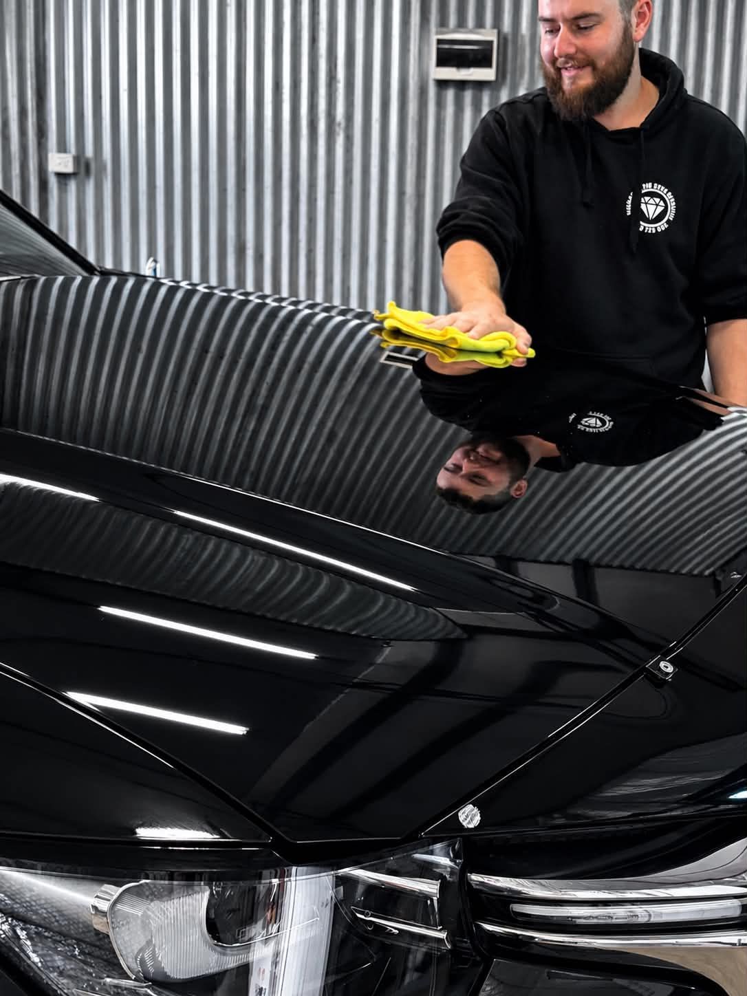 Black SUV Parked on A Slanted Street Beside a Yellow Gate and Building — Diamond Glow Auto Detailing in Armidale, NSW