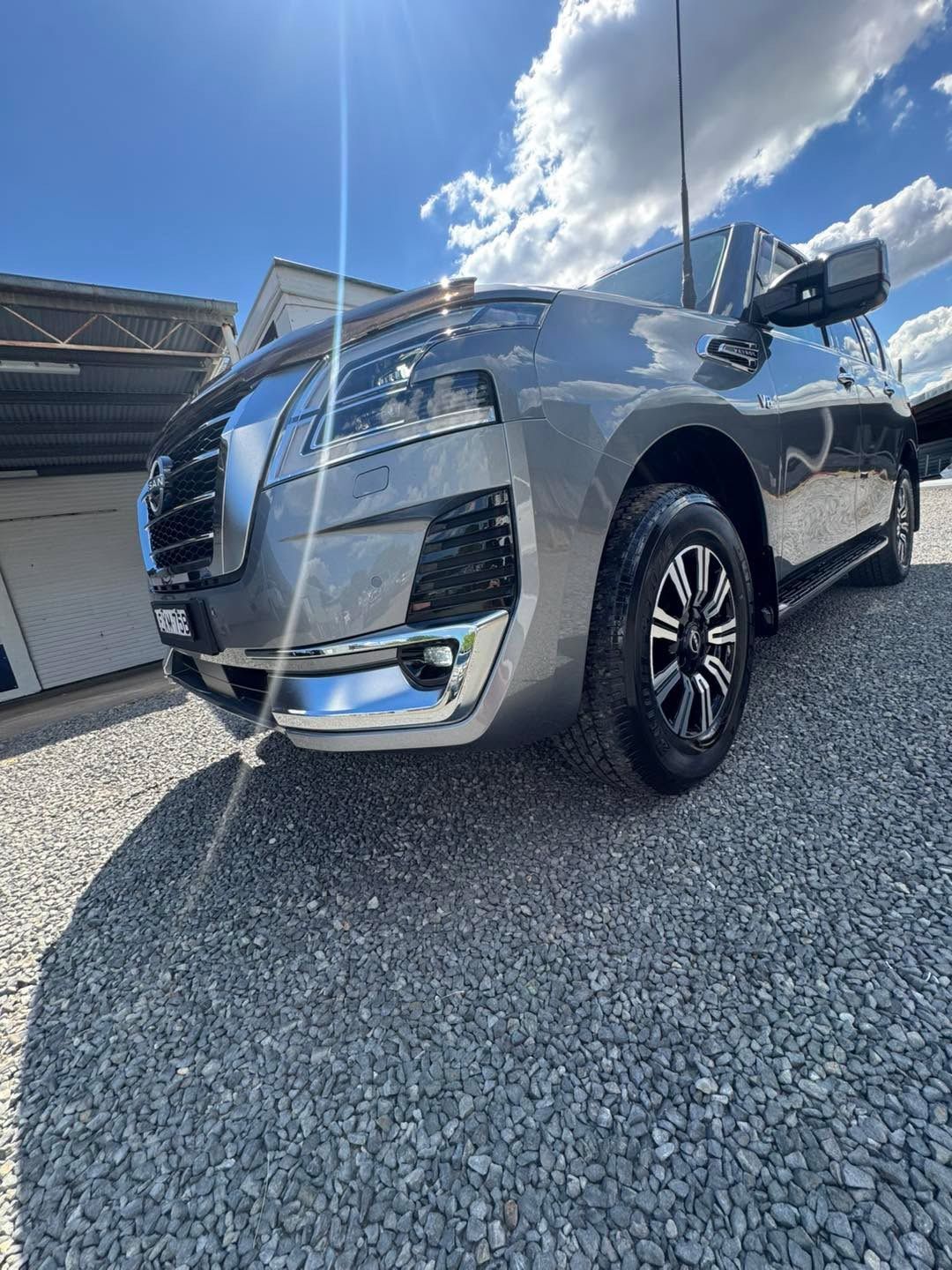 Silver SUV parked on gravel beside a building, viewed from a low angle under a bright blue sky — Diamond Glow Auto Detailing in Armidale, NSW