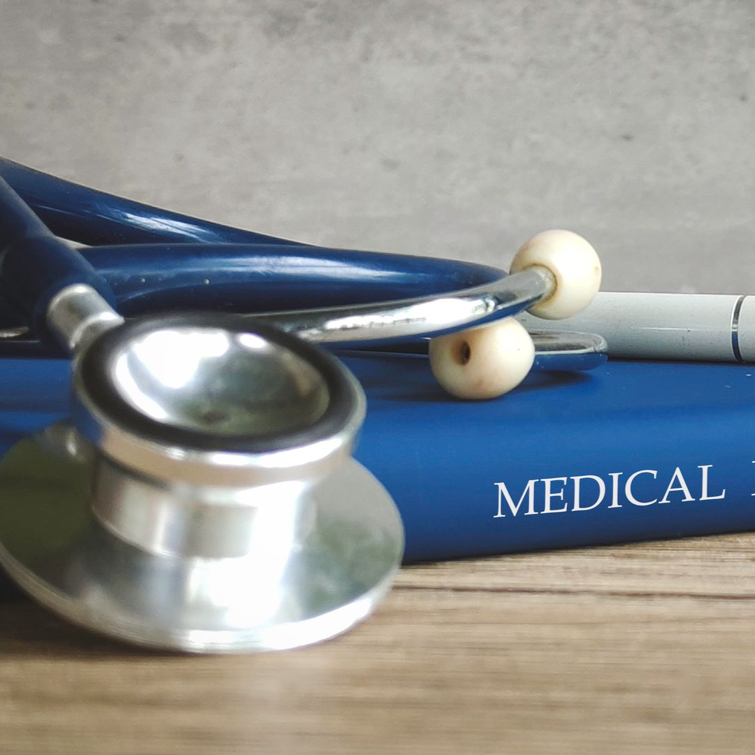 Stethoscope on a blue medical textbook. White ear pieces and silver metal.