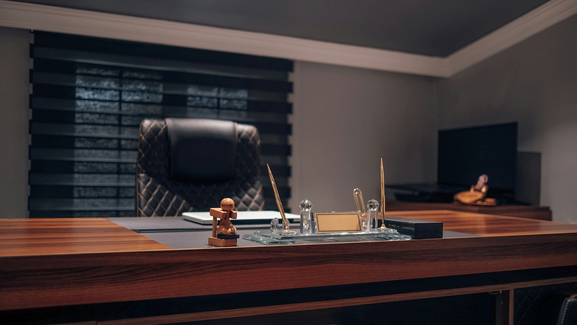Dark wood office with black leather chair, desk accessories, and a Buddha statue.