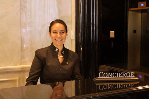 Concierge desk with a smiling staff member standing behind the counter in a hotel lobby