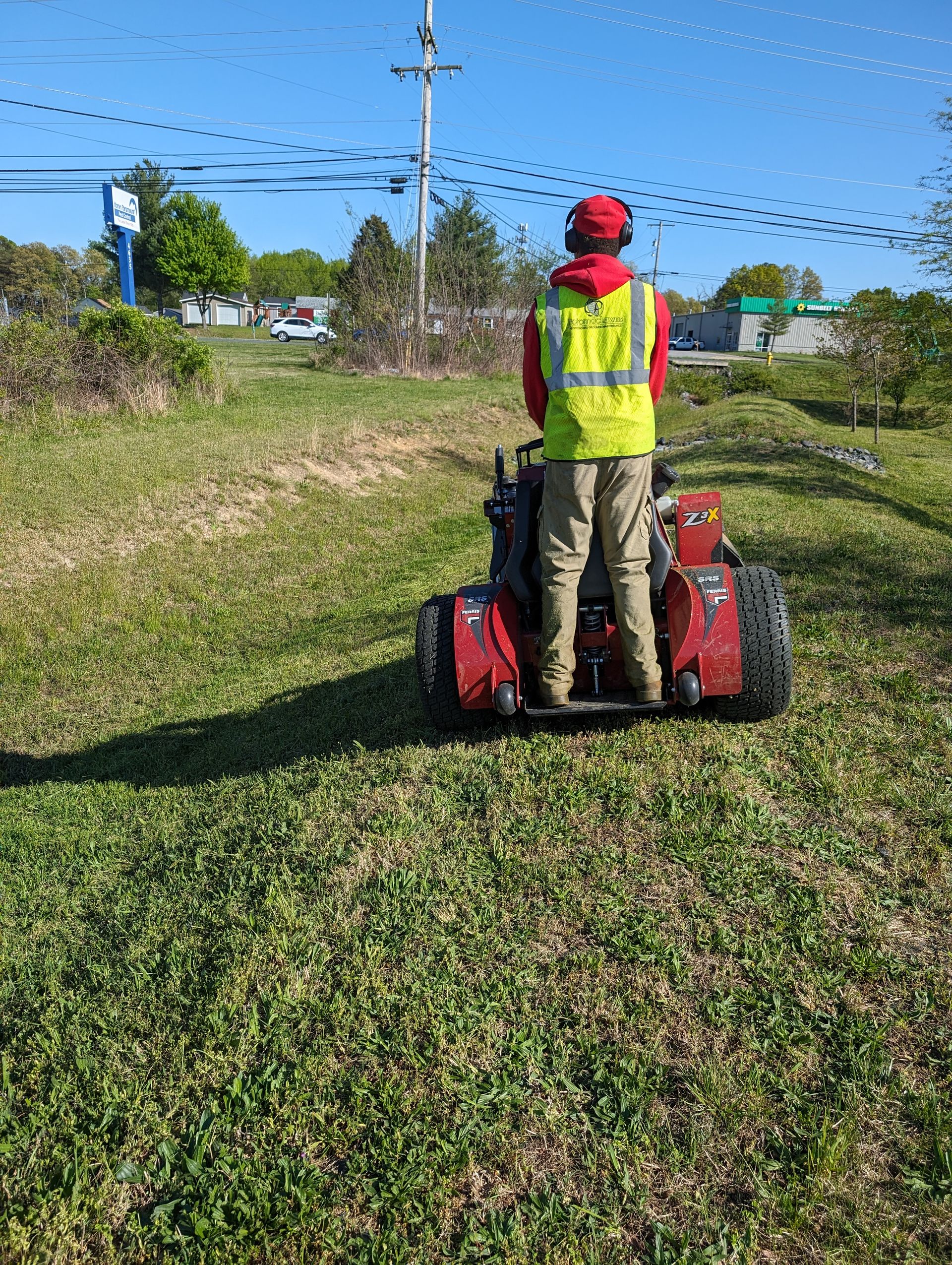 A man is riding a lawn mower on a lush green lawn.