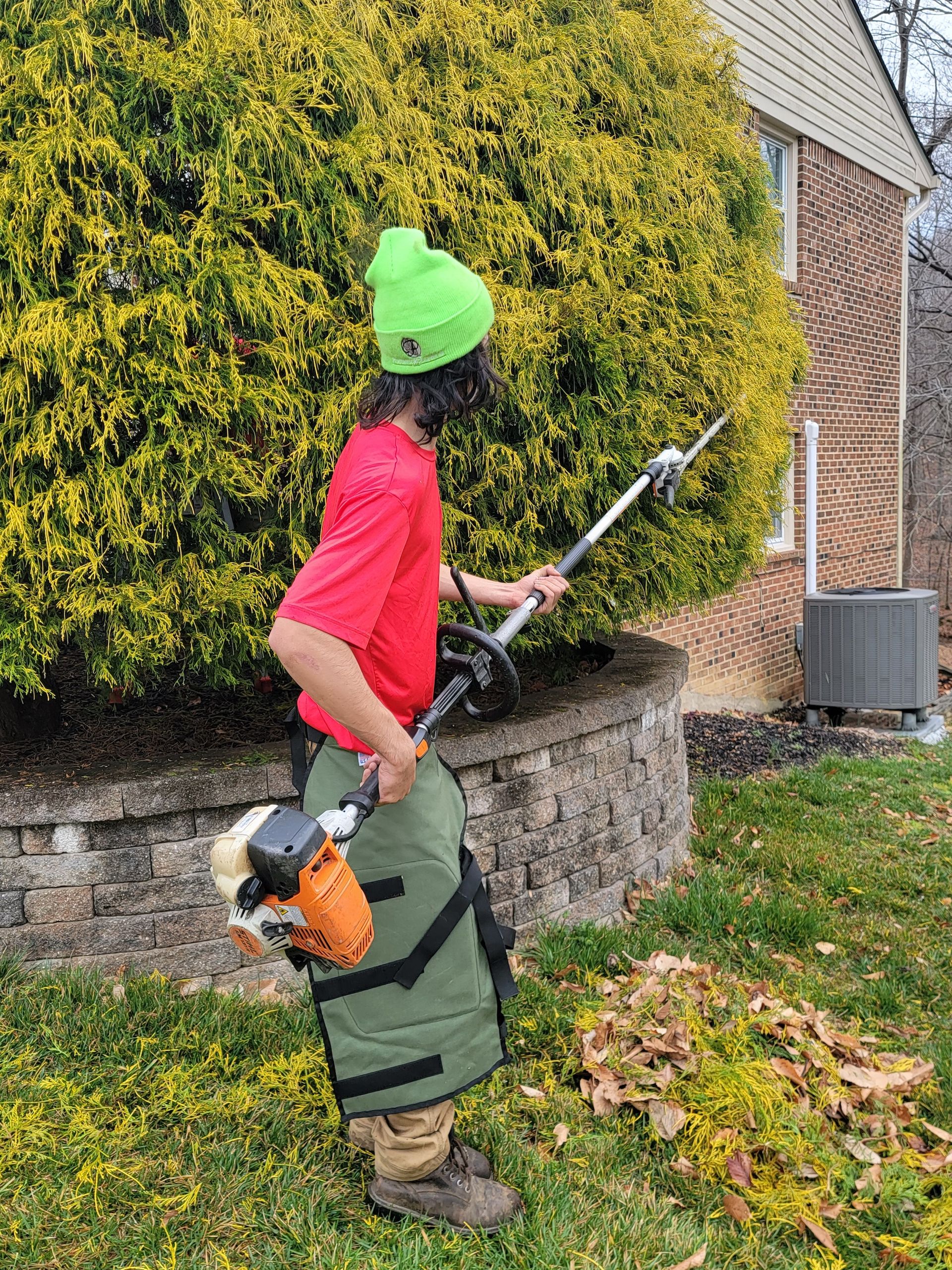 A man is cutting a bush with a lawn mower.