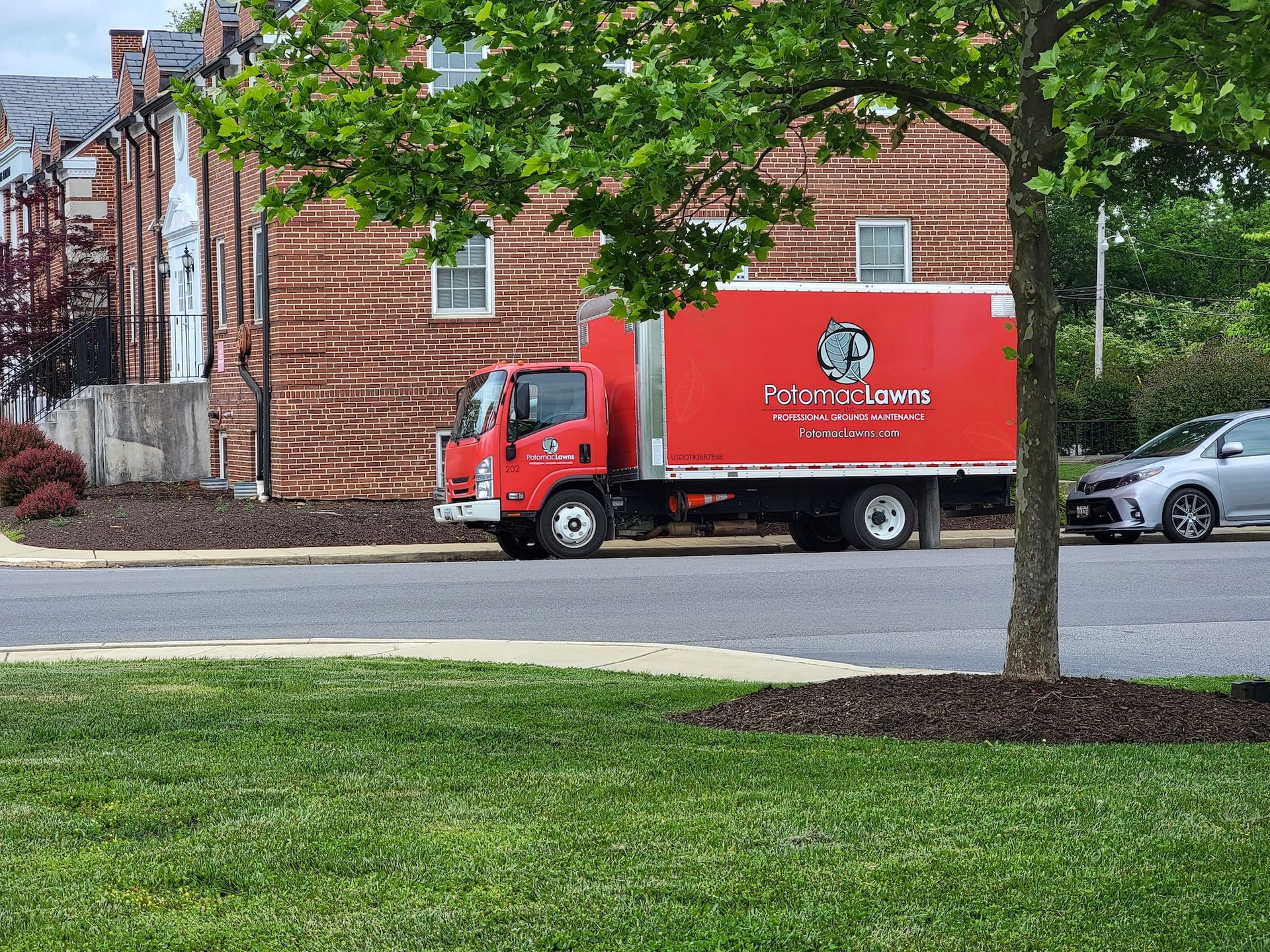 A red moving truck is parked on the side of the road in front of a brick building.