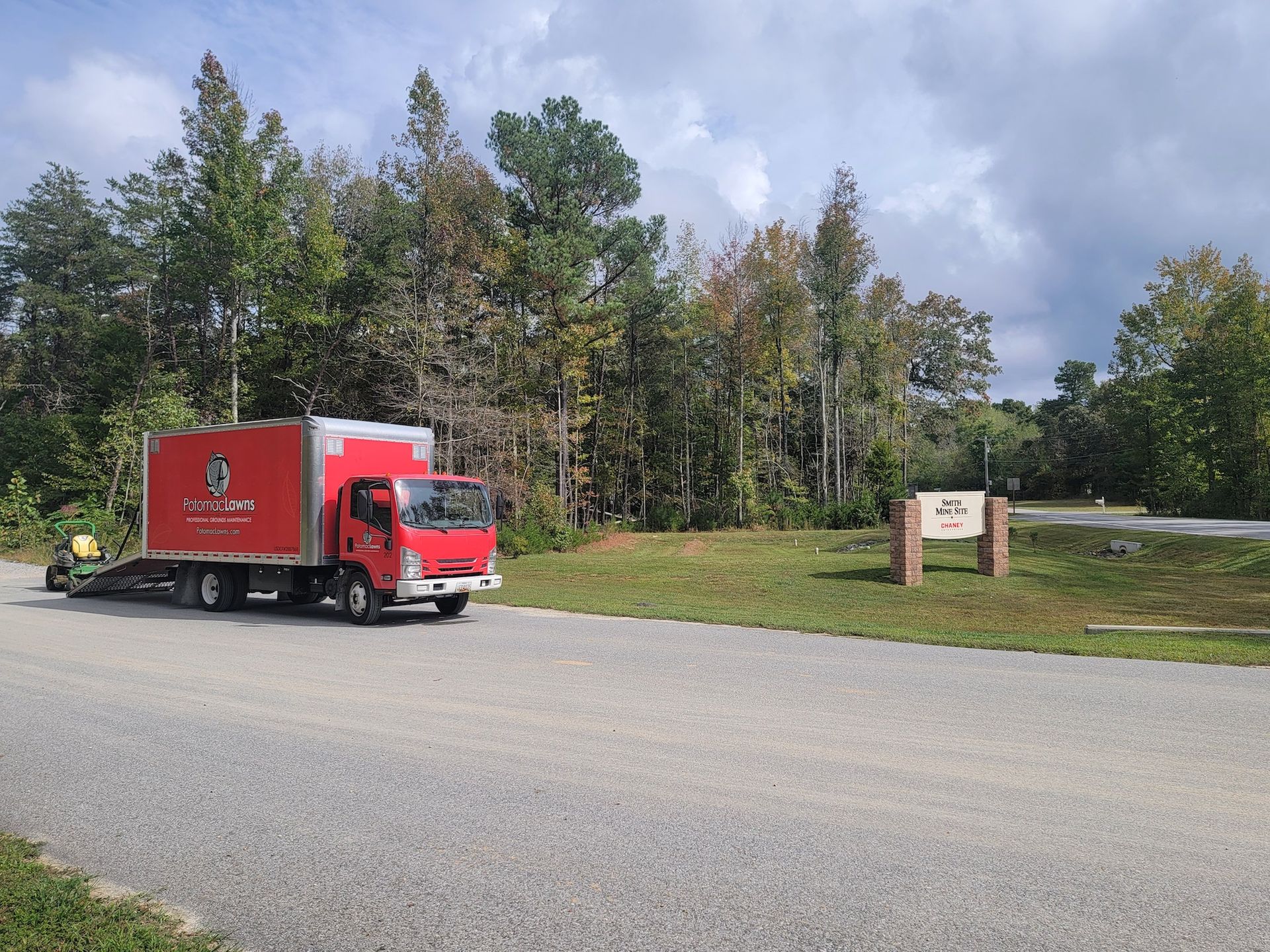 A red truck is driving down a road with a trailer attached to it.