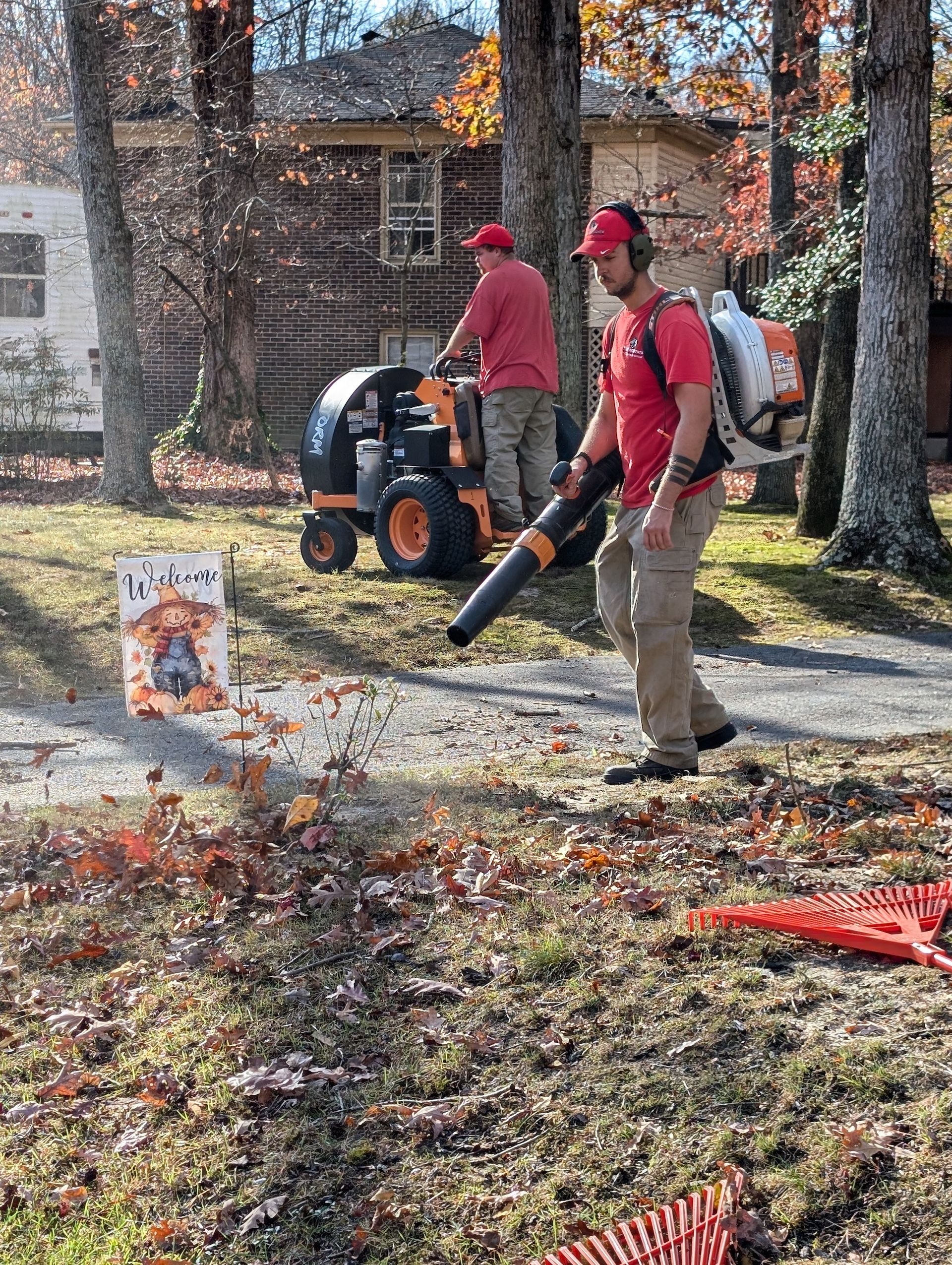 A person is blowing leaves in the grass with a blower.