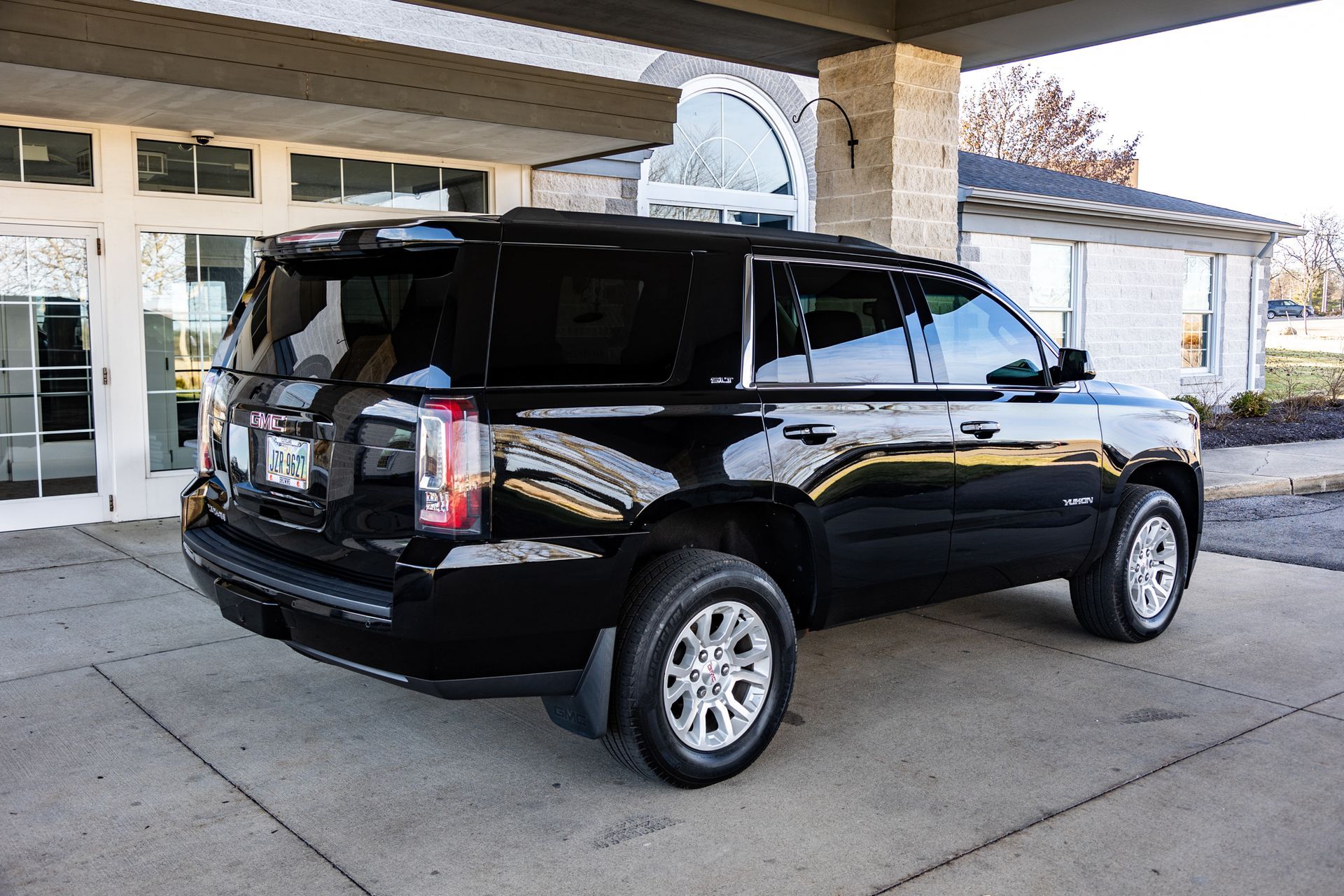 A black suv is parked in front of a building.