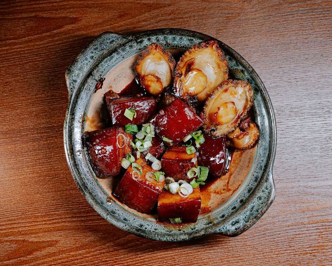 Glazed cubes and roasted chunks with chopped green herbs in a rustic ceramic bowl on a wooden table