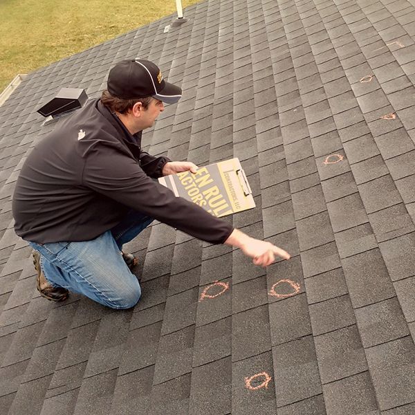 Man inspecting hail damage on a roof 