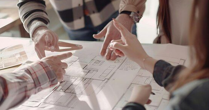 People's hands pointing at a blueprint, discussing design plans.