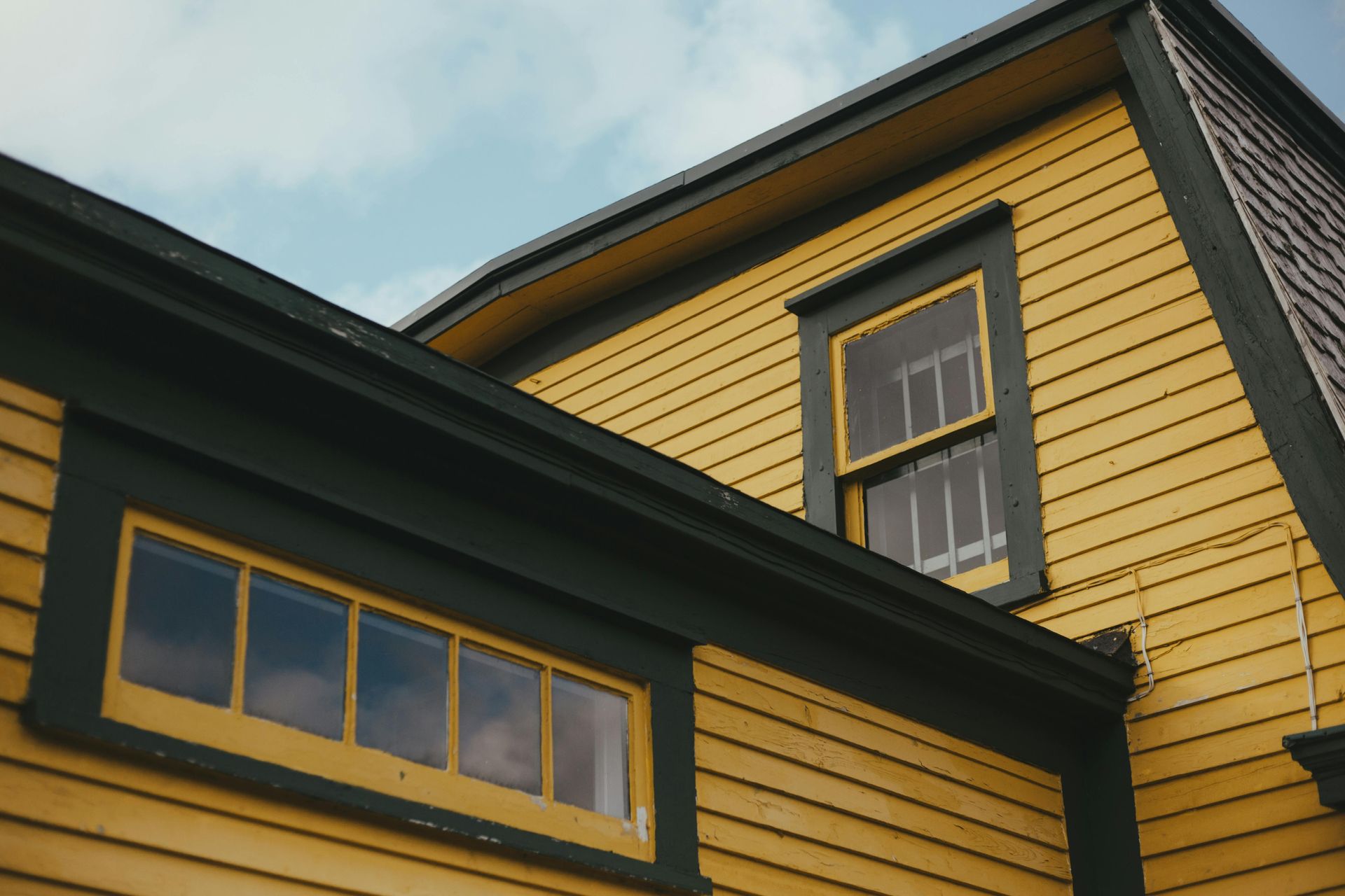 Yellow house exterior with black trim and windows viewed from below