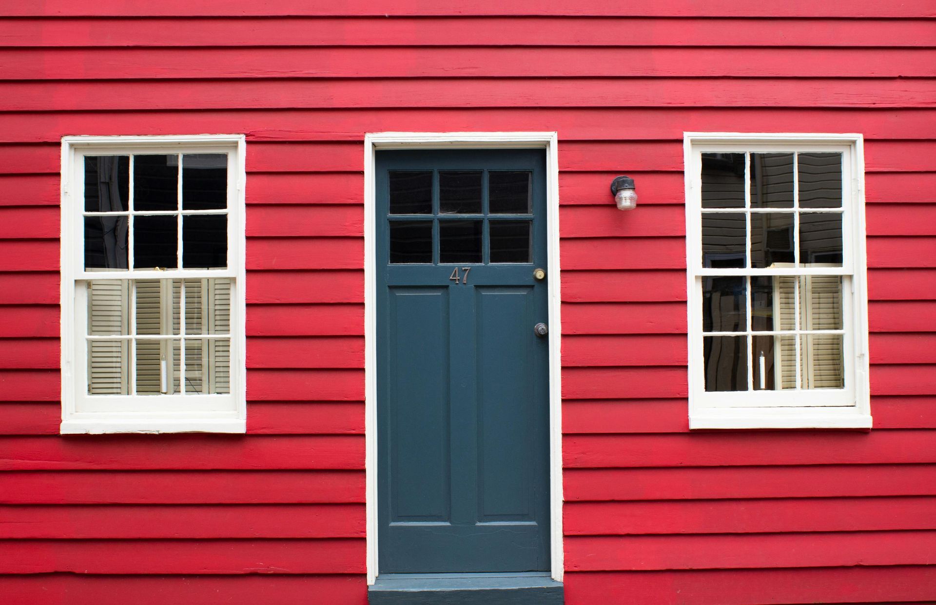 Red house exterior with a blue door and two white-trimmed windows
