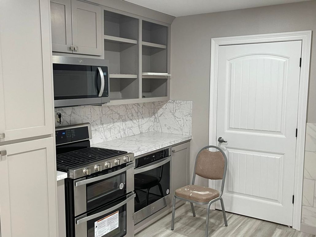 A kitchen with a stove , oven , microwave and chair.