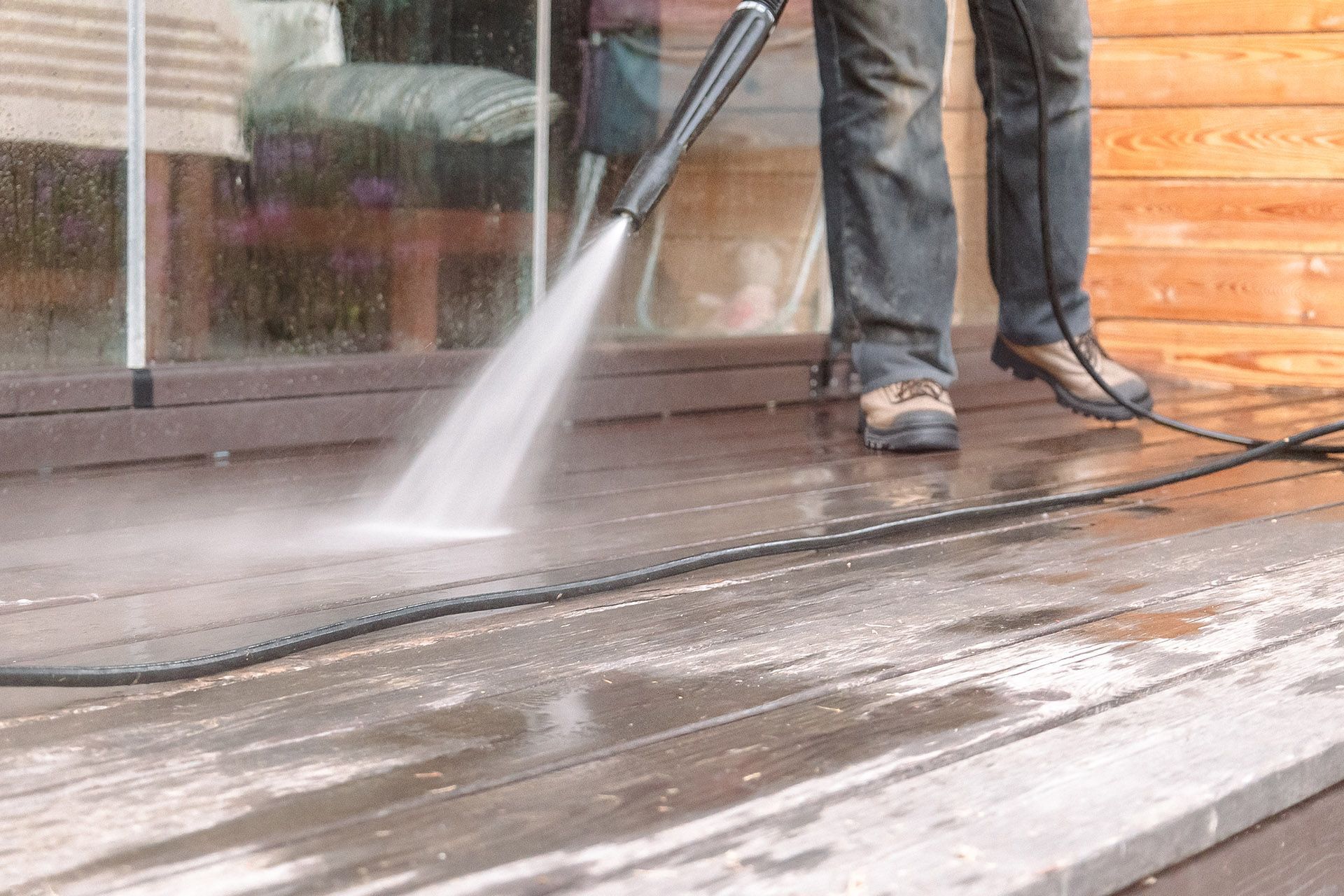 Person power washing a wooden deck.