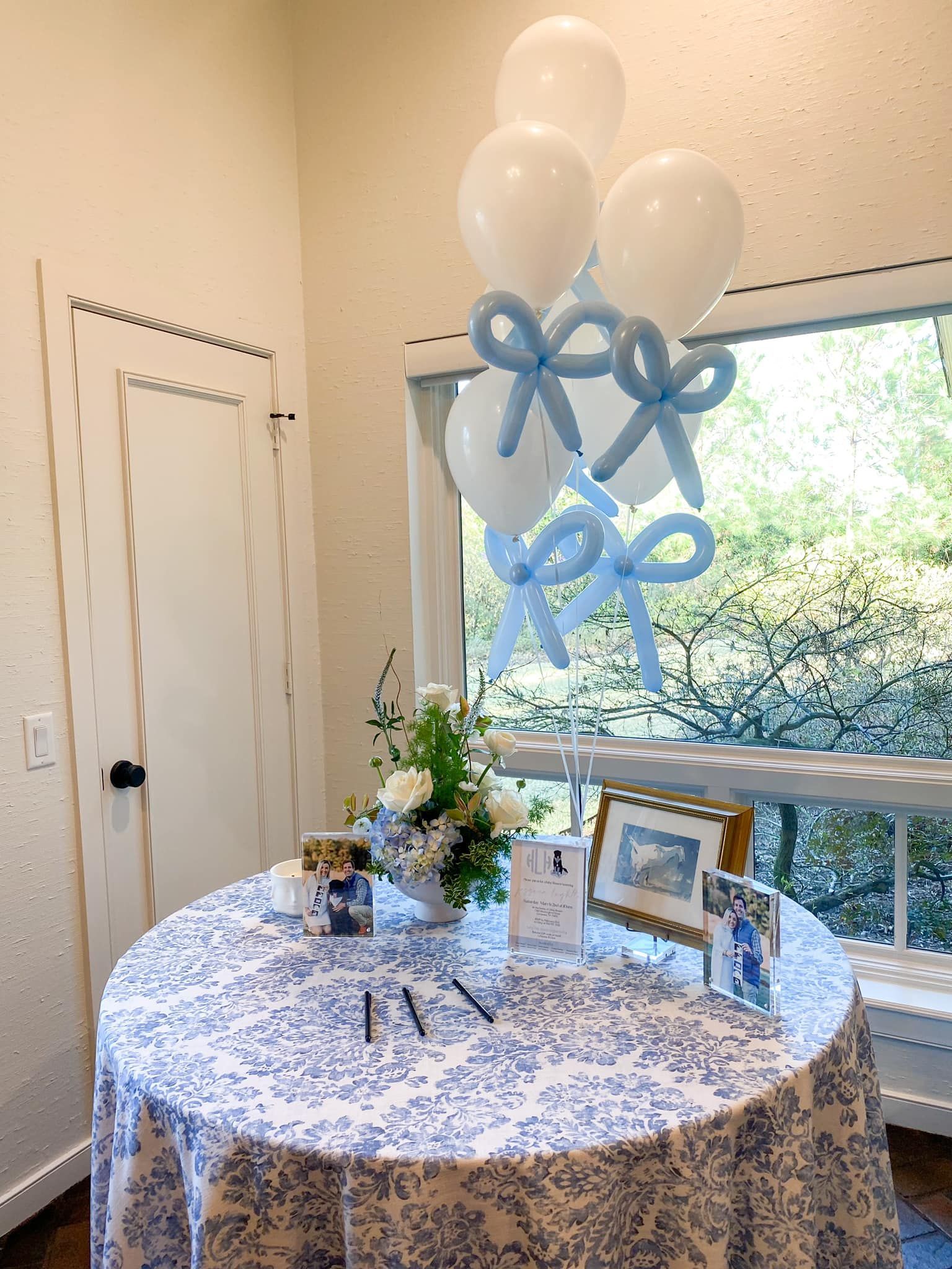 Round table with blue floral tablecloth, balloons, and decorations.