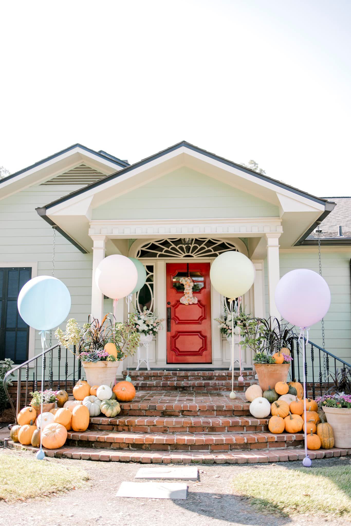 House front entrance decorated with pumpkins and pastel balloons.