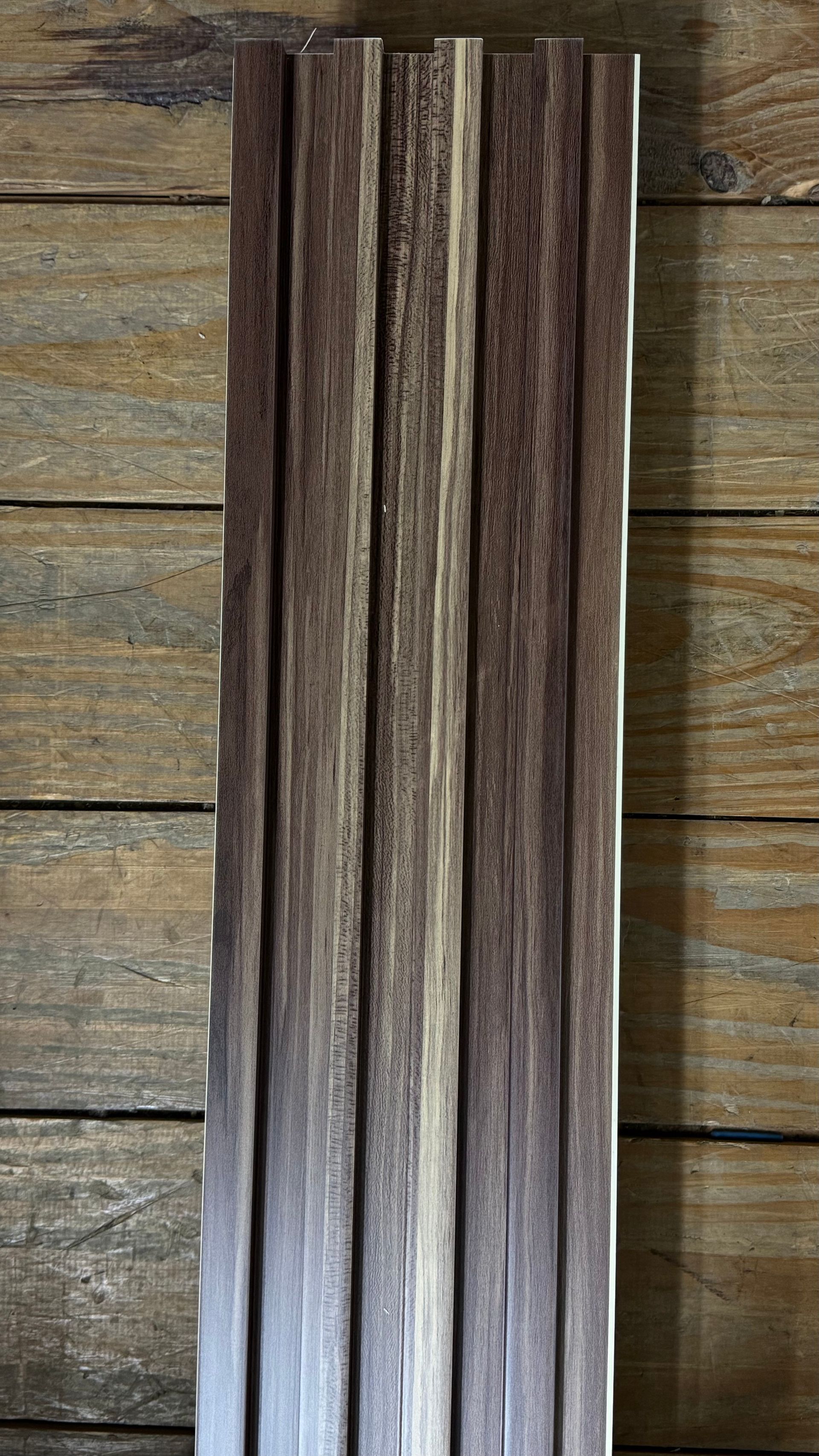 Listones verticales de madera oscura sobre un fondo de madera envejecida.