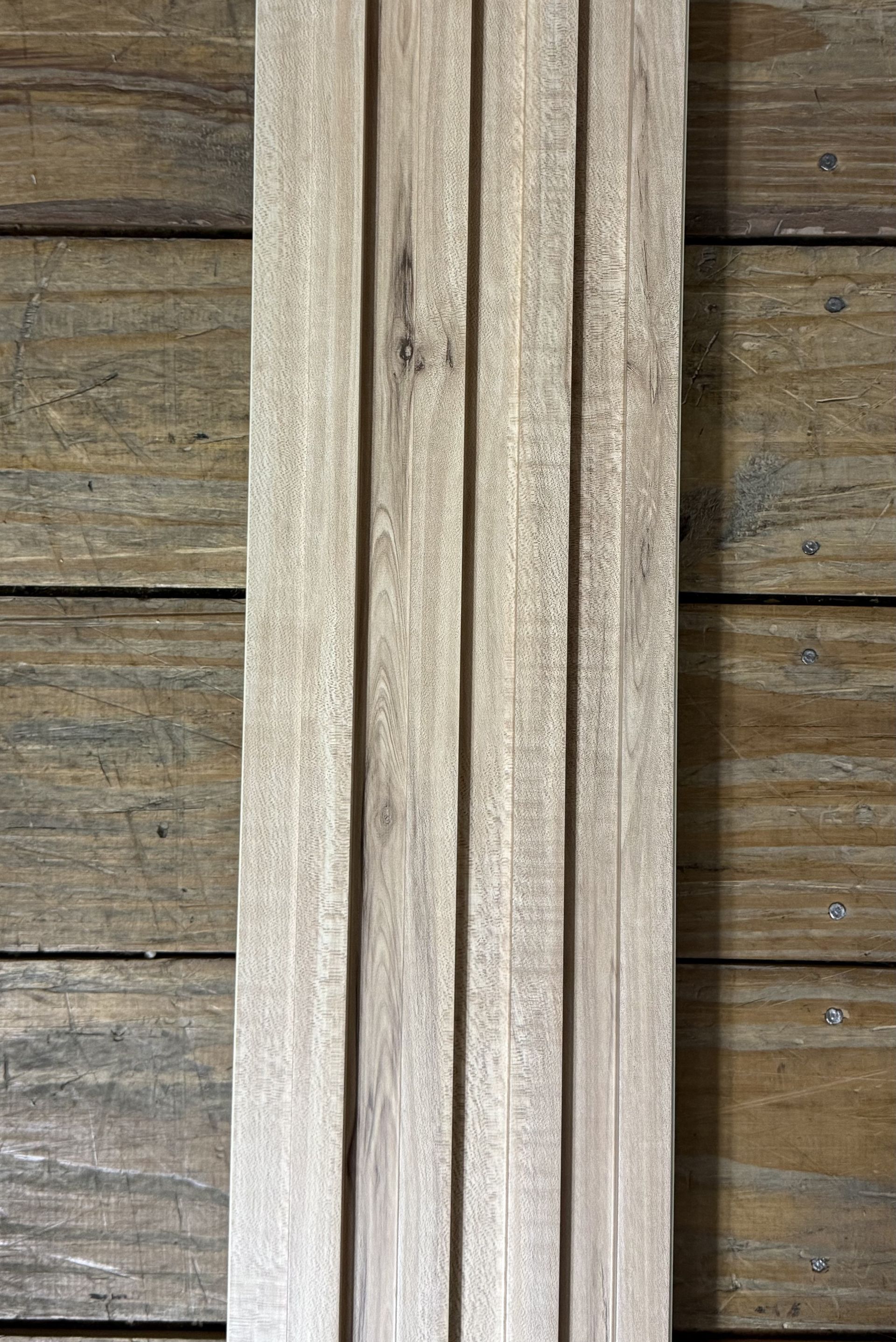 Tablas de madera desgastadas en posición vertical en una estructura rústica de pared o cerca de color gris parduzco.