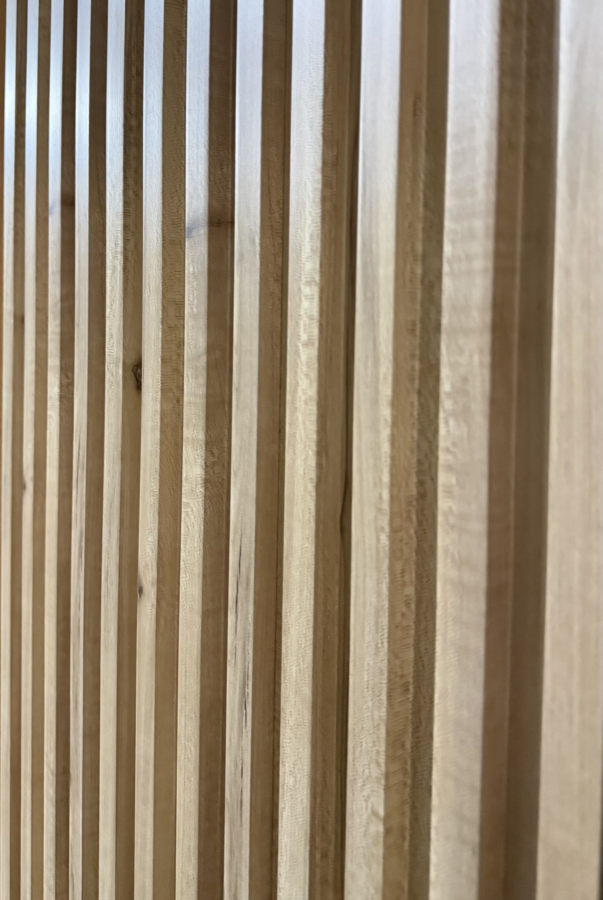 Tablas de madera desgastadas en posición vertical en una estructura rústica de pared o cerca de color gris parduzco.