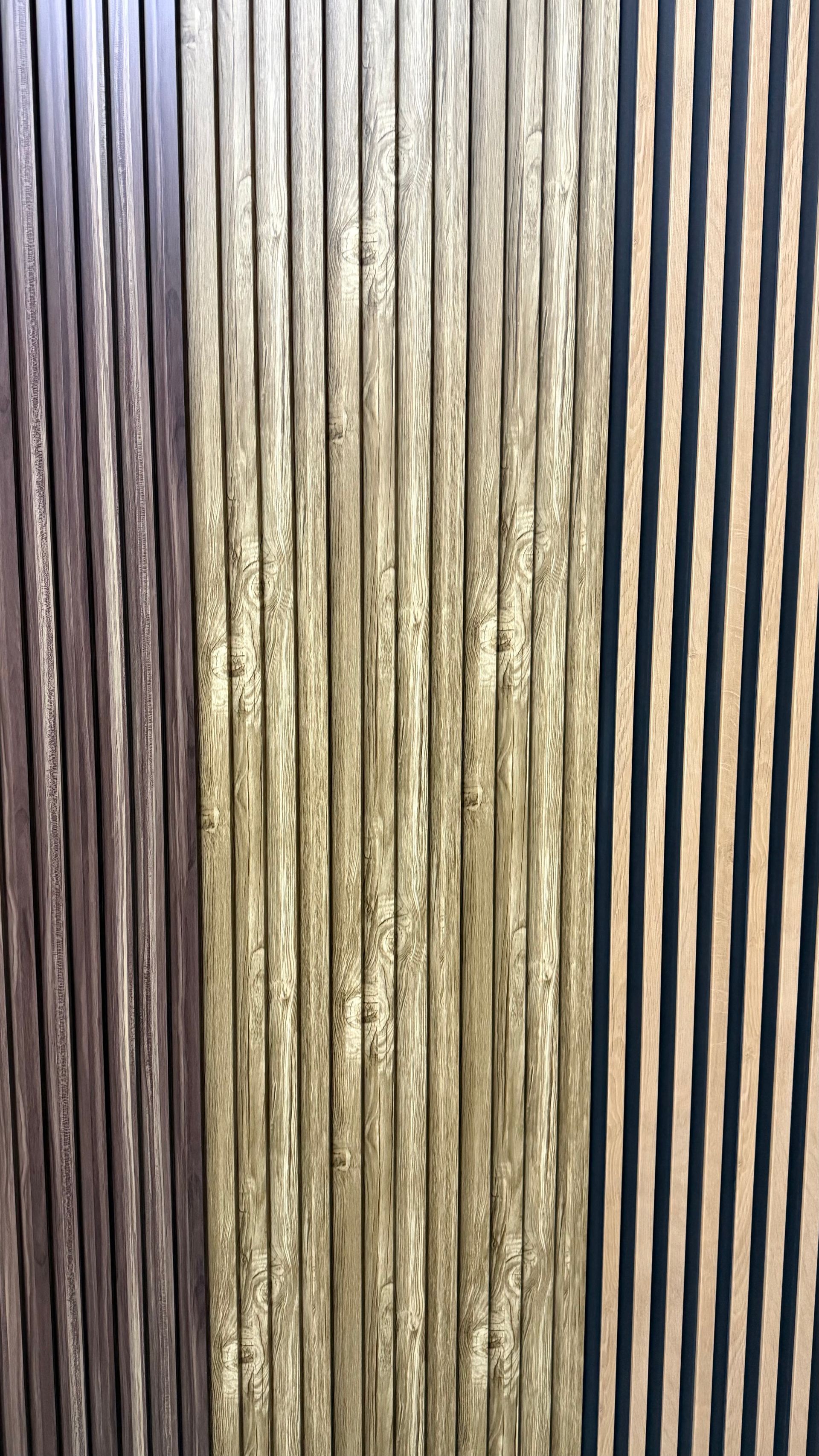 Primer plano vertical de estrechas lamas de madera marrón con la luz reflejándose entre ellas.