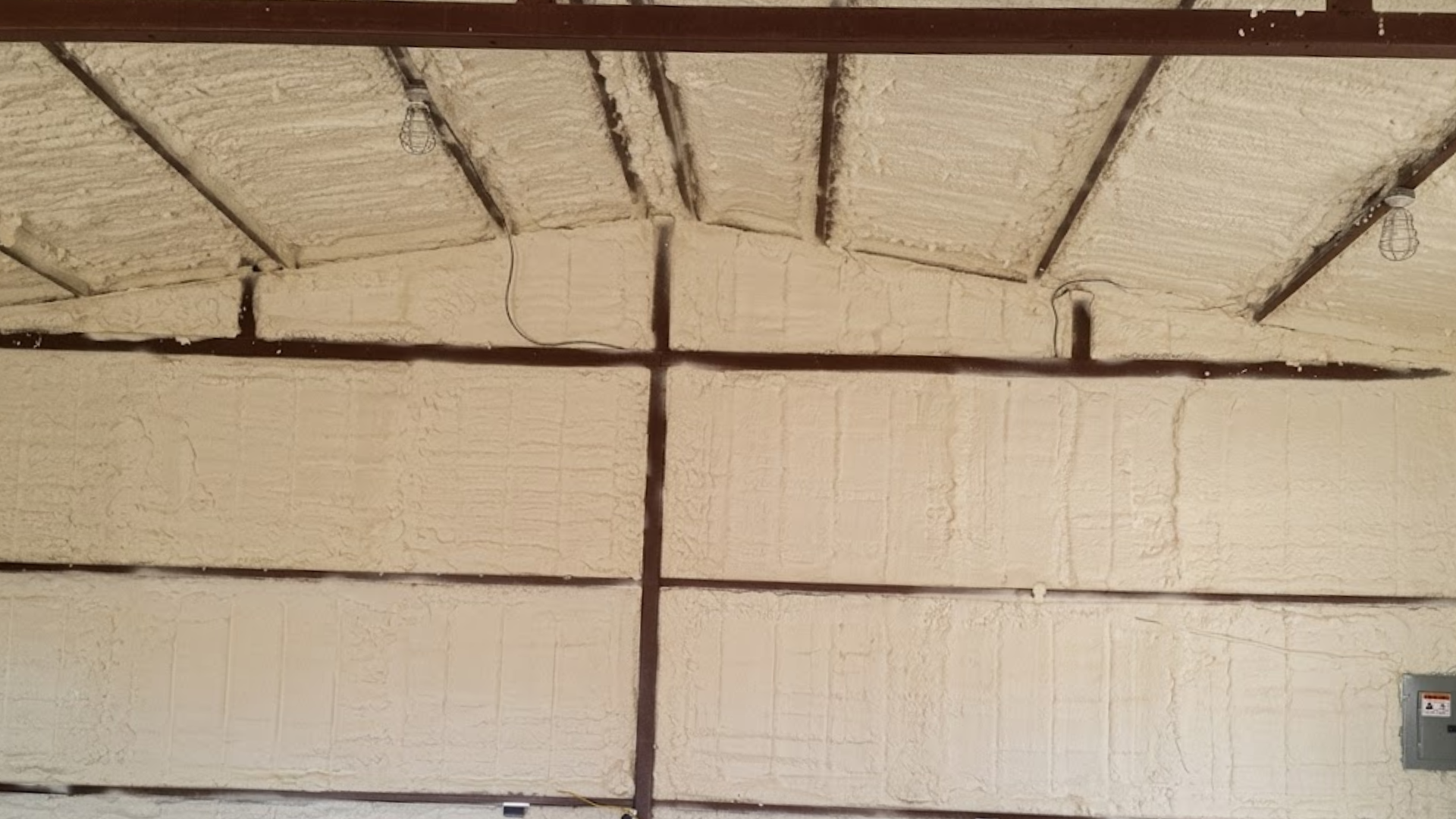Interior ceiling with corrugated metal roof and beige wall panels, lit by daylight.
