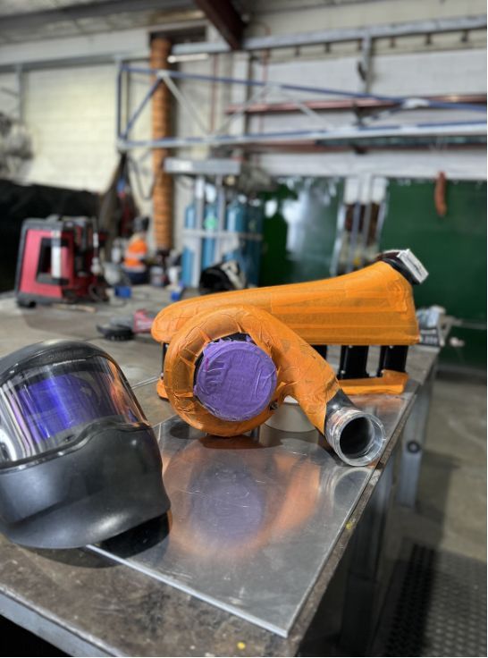 A Welding Helmet And A Turbocharger Are Sitting On A Table — Hanby Welding & Engineering In Portsmith, QLD