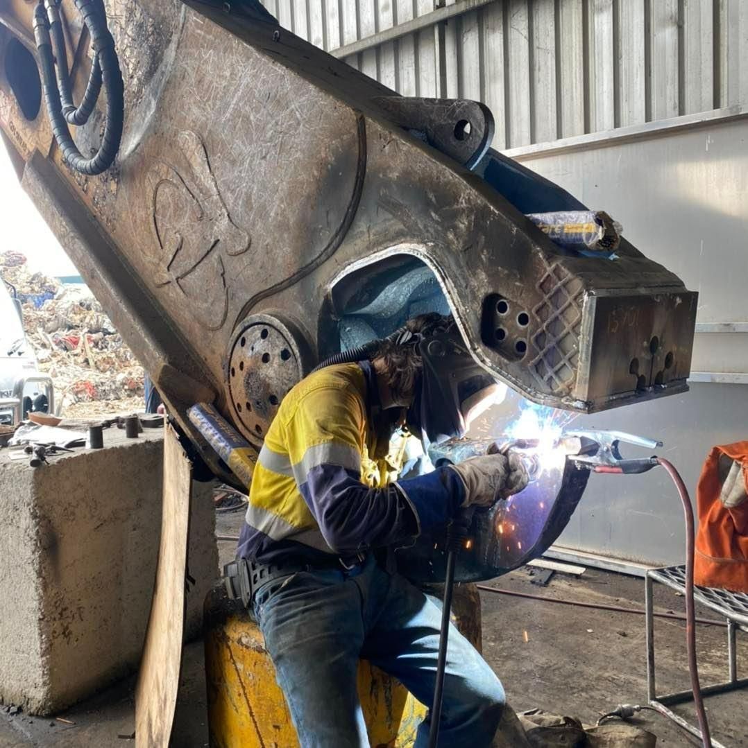 A Man Wearing A Welding Helmet Is Welding A Piece Of Metal — Hanby Welding & Engineering In Portsmith, QLD