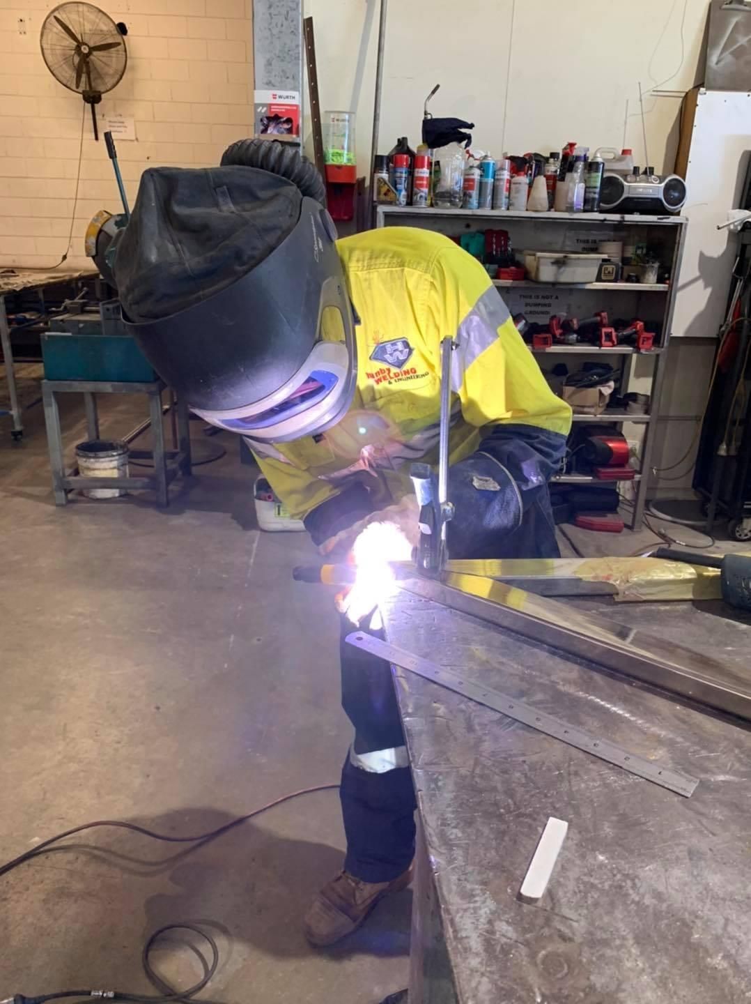 A Man Is Welding A Piece Of Metal In A Garage — Hanby Welding & Engineering In Portsmith, QLD