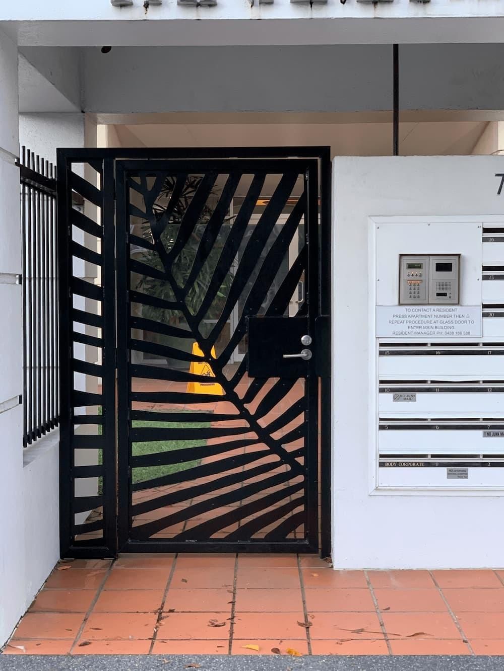 A Black Gate With A Leaf Design Is In Front Of A Building — Hanby Welding & Engineering In Portsmith, QLD