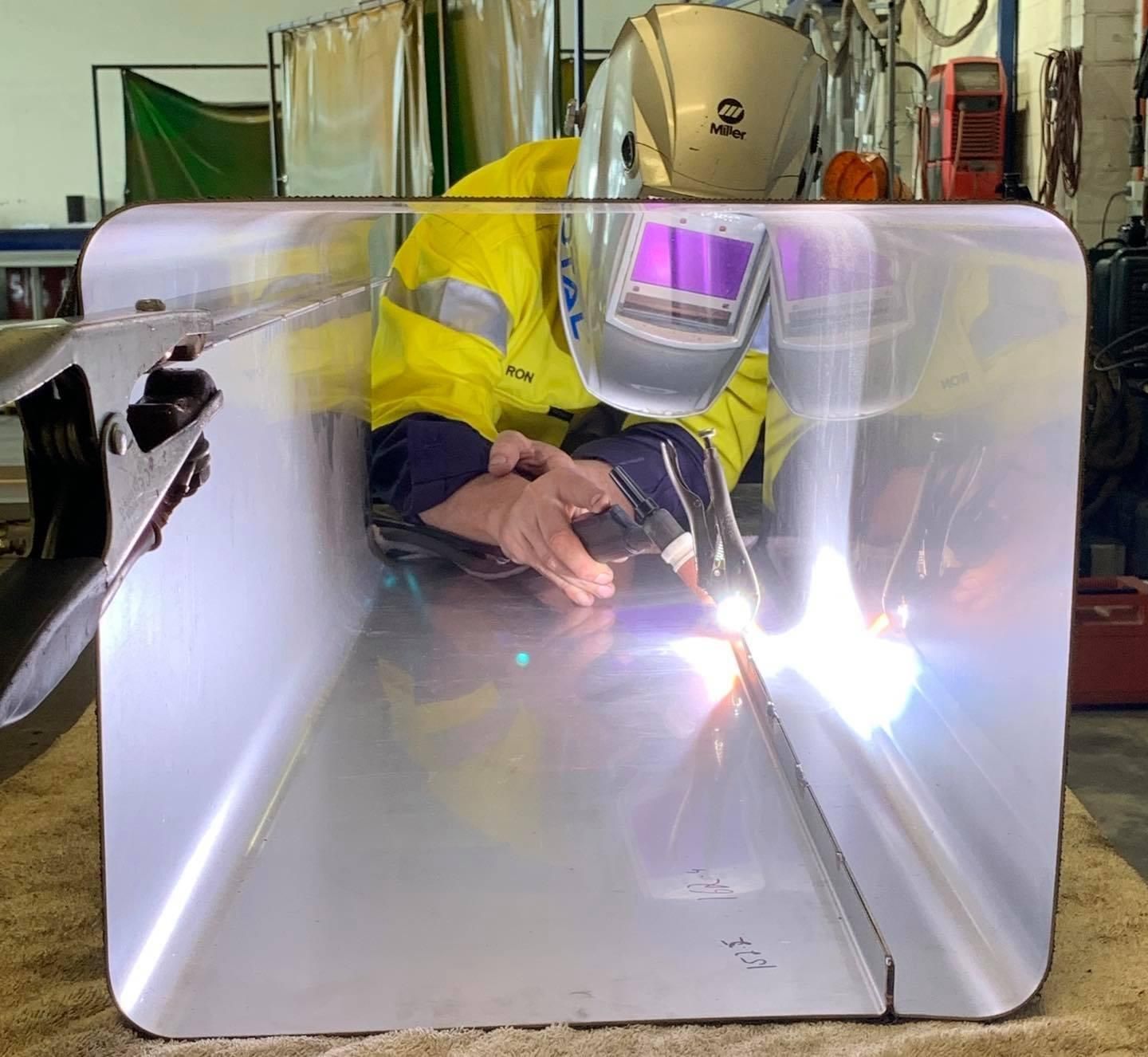 A Man Wearing A Welding Mask Is Welding A Piece Of Metal — Hanby Welding & Engineering In Portsmith, QLD